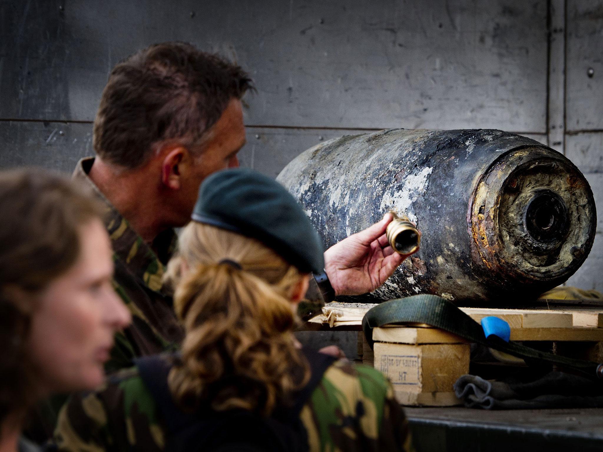 Members of the Dutch Explosive Ordnance Disposal unit stand next to a 500-pound bomb from World War II in Wannenaar, the Netherlands