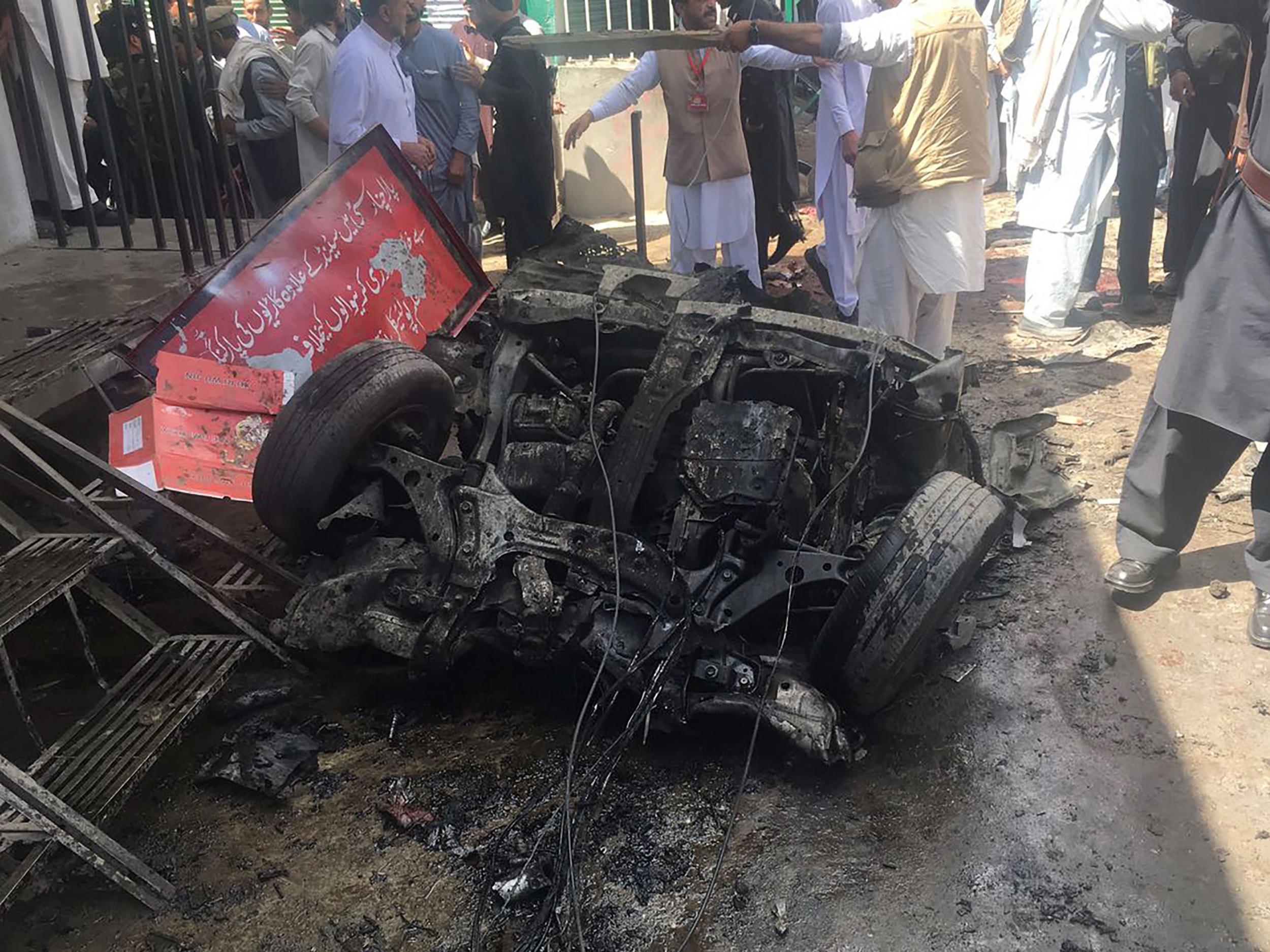 Pakistani security officials and residents gather at the site of a powerful explosion at a market in Parachinar