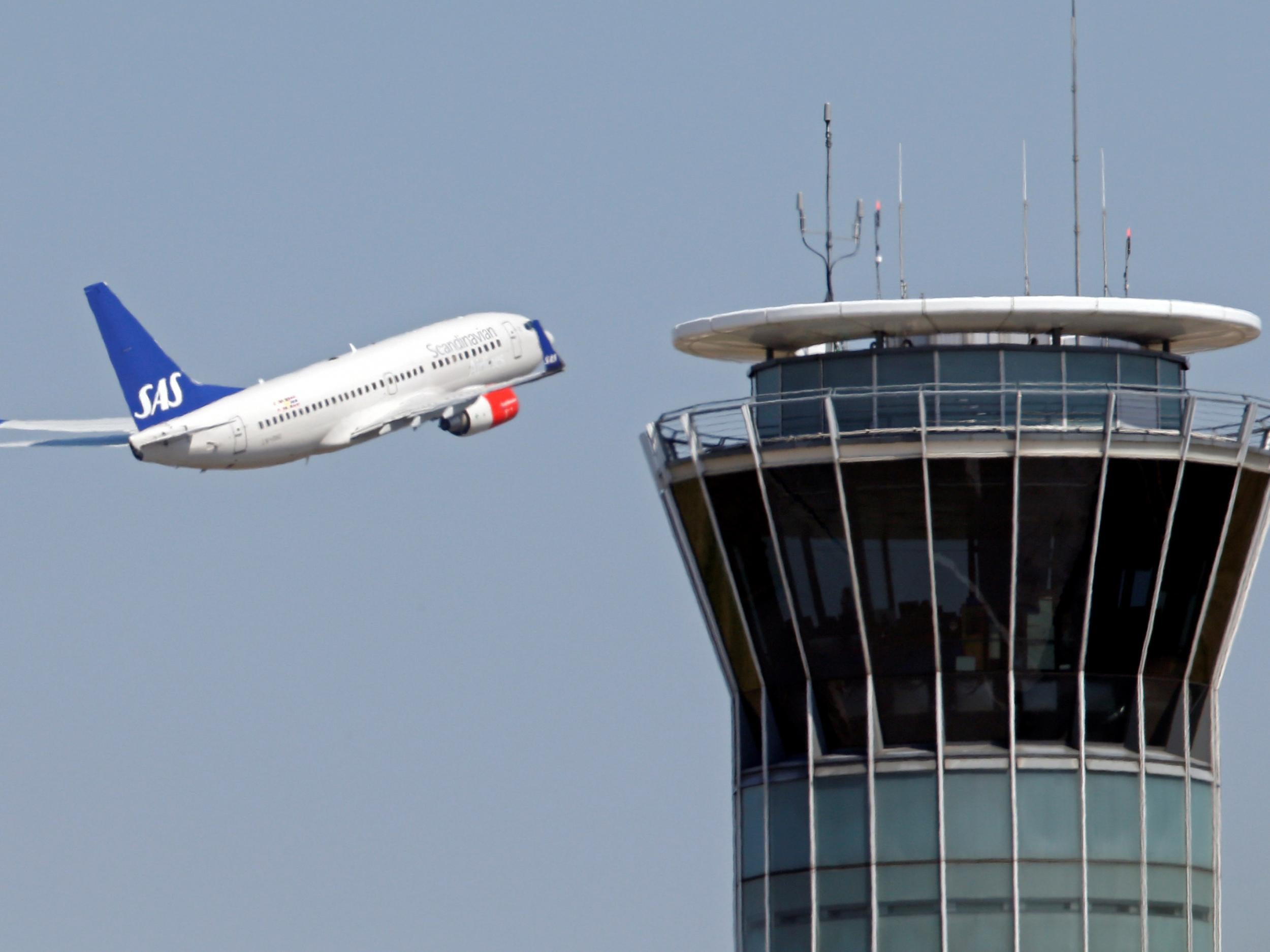 A passenger plane flies by an air traffic control tower after taking off from Charles de Gaulle International Airport