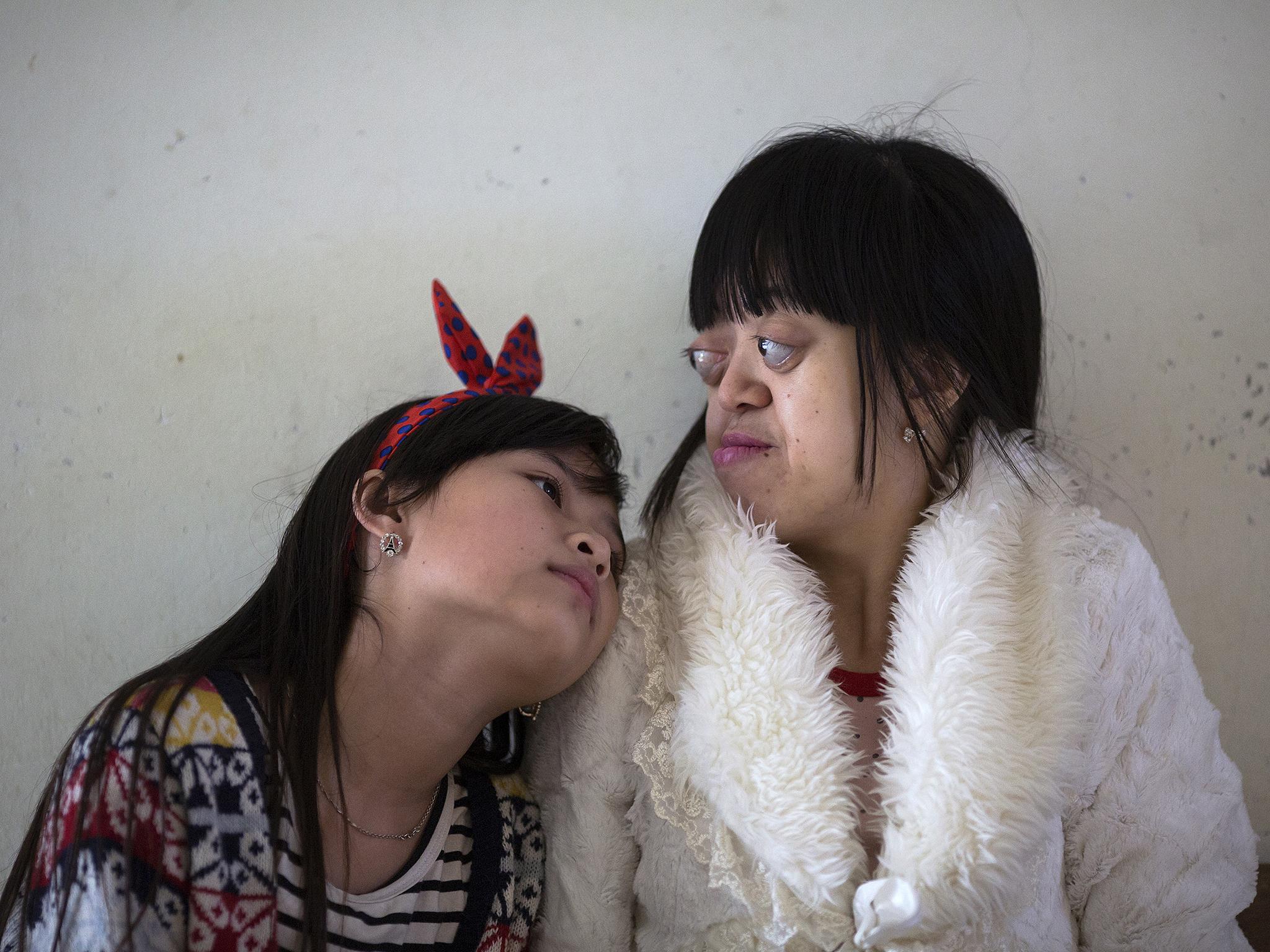 Nguyen Thi Van Long (R) and her best friend Dinh Thi Huong, who is deaf and mute, spend time together at Friendship village, a hospice for Agent Orange victims outside Hanoi