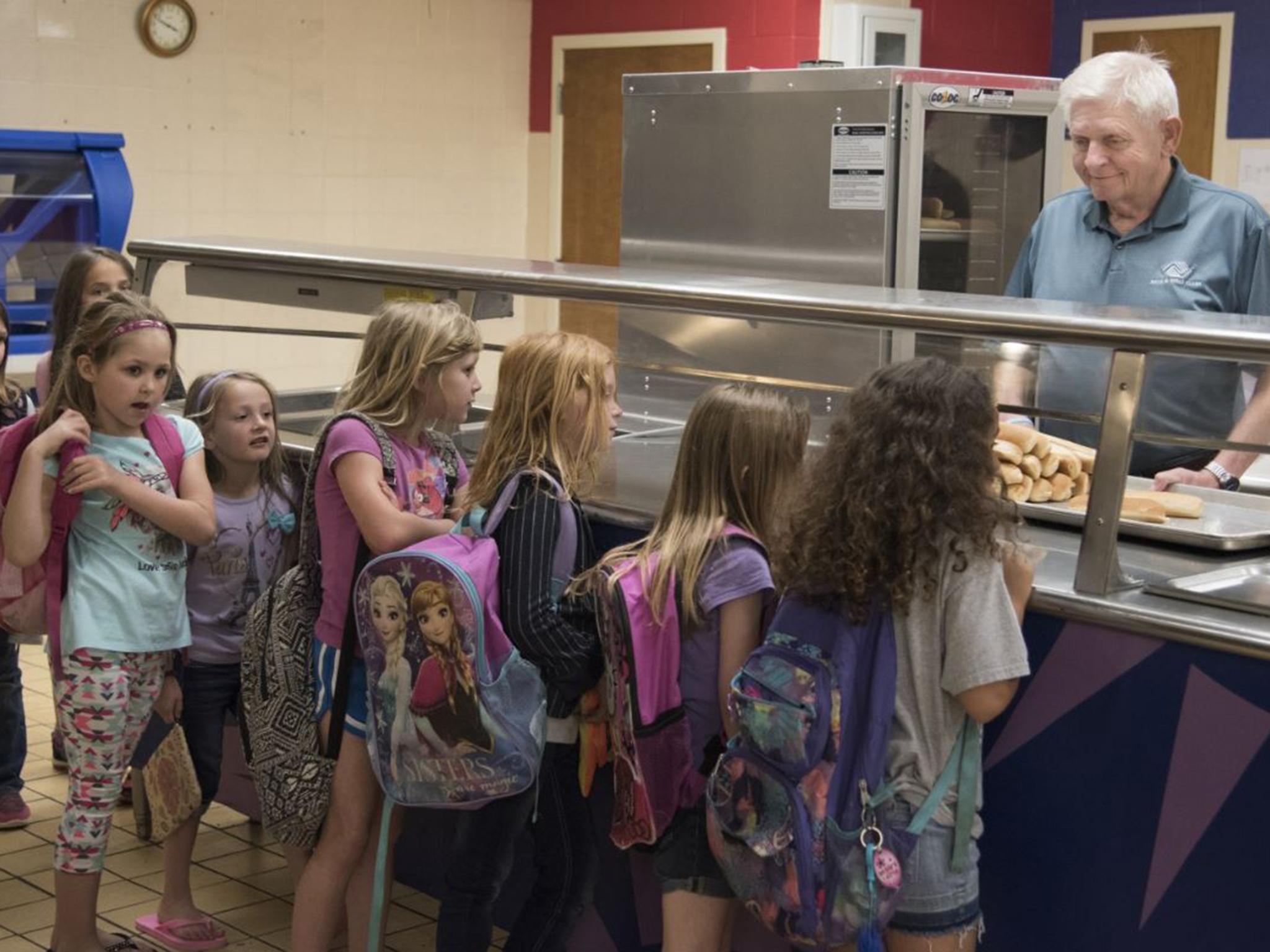 Larry Long, director of the Durant Boys and Girls Club, helps serve hot dogs to children there