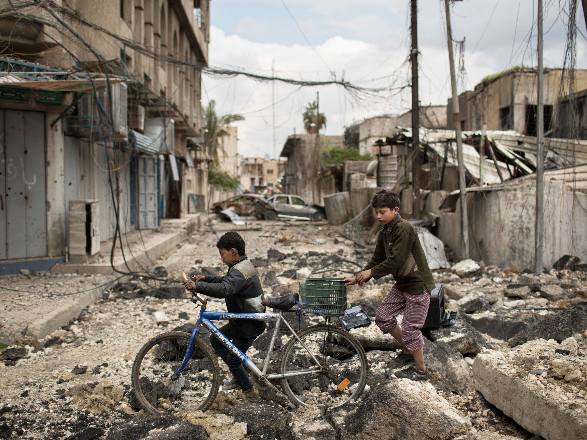 Iraqi boys walk on a destroyed street in a neighborhood recently retaken by Iraqi security forces during fighting against Islamic State militants on the western side of in Mosul