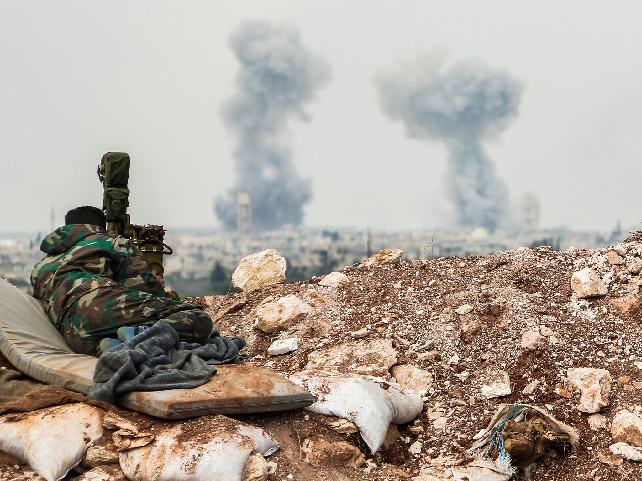 A Syrian forces' artillery observer looks through a scope as smoke plumes rise on the horizon, near the town of Qumhanah in the countryside of the central province of Hama, on April 1, 2017.