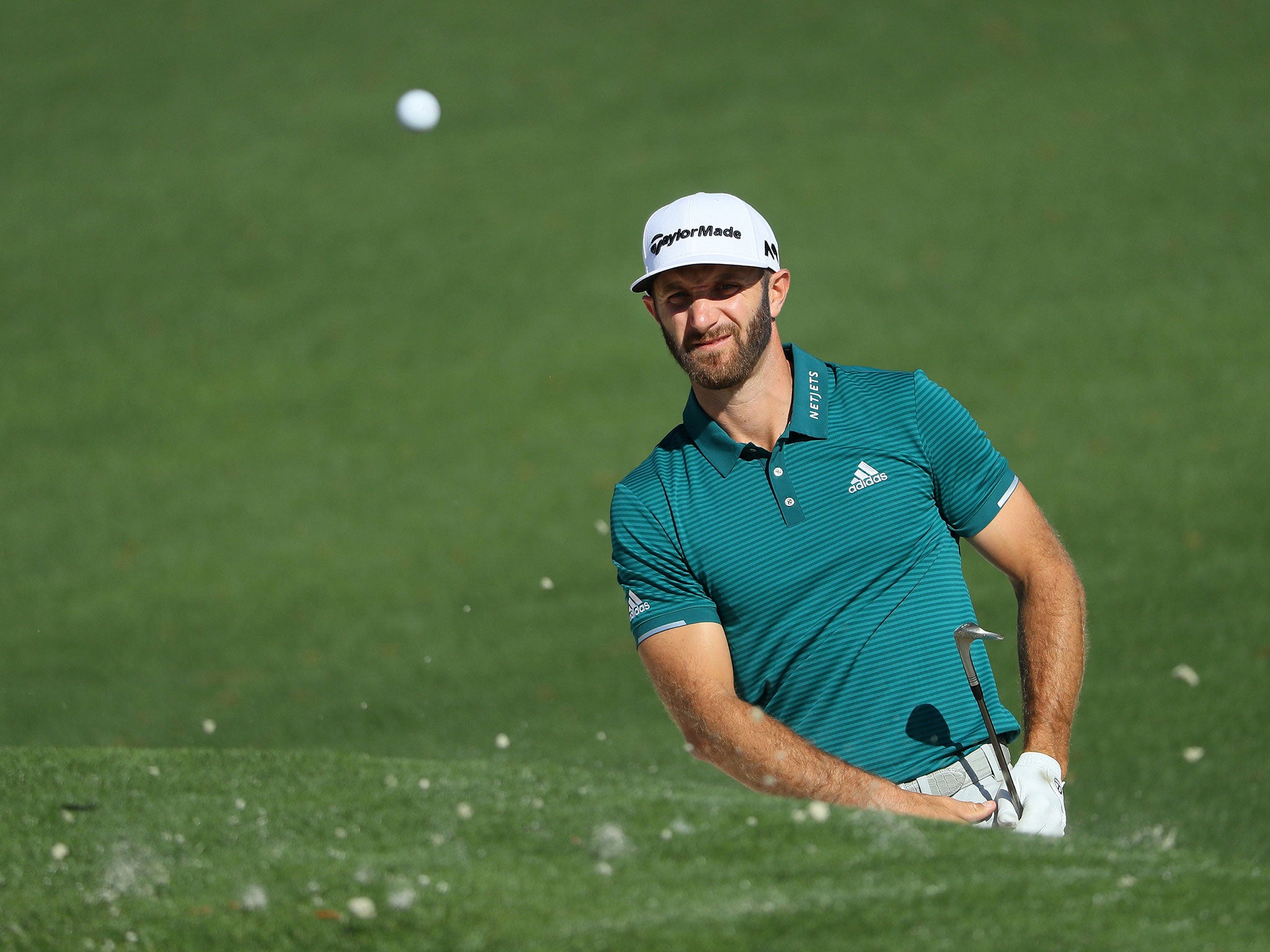 Johnson plays a shot from a bunker on the second hole during a practice round