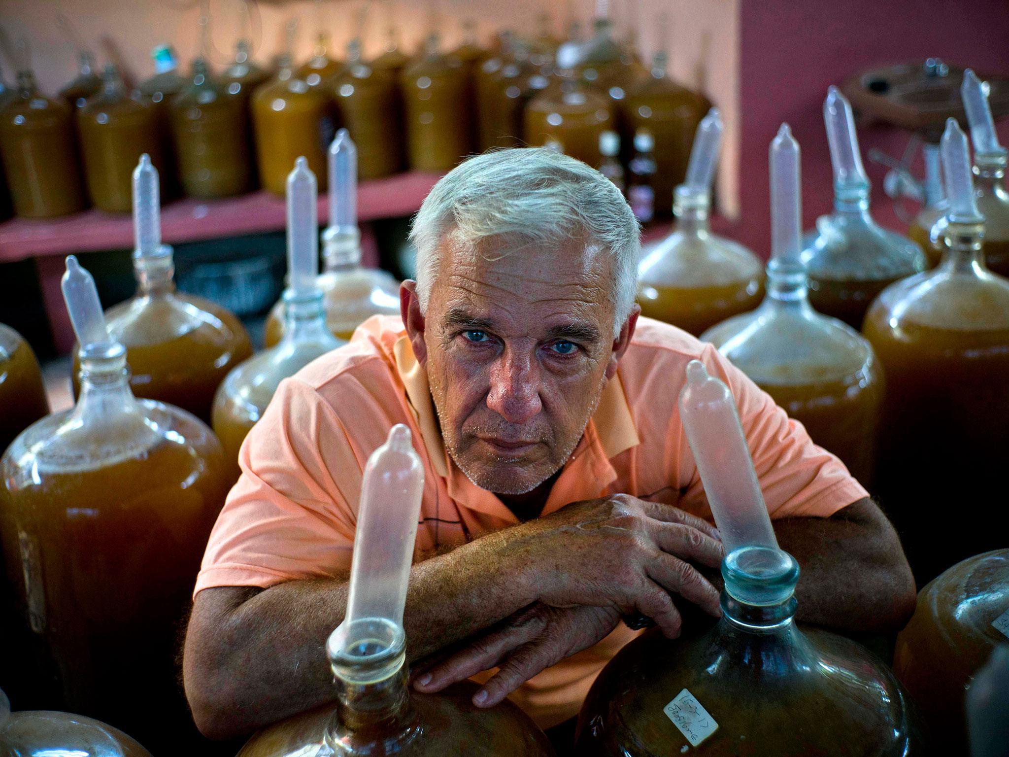 Orestes Estevez and his family fill glass jugs with grapes, ginger and hibiscus before securing a condom over each glass jug