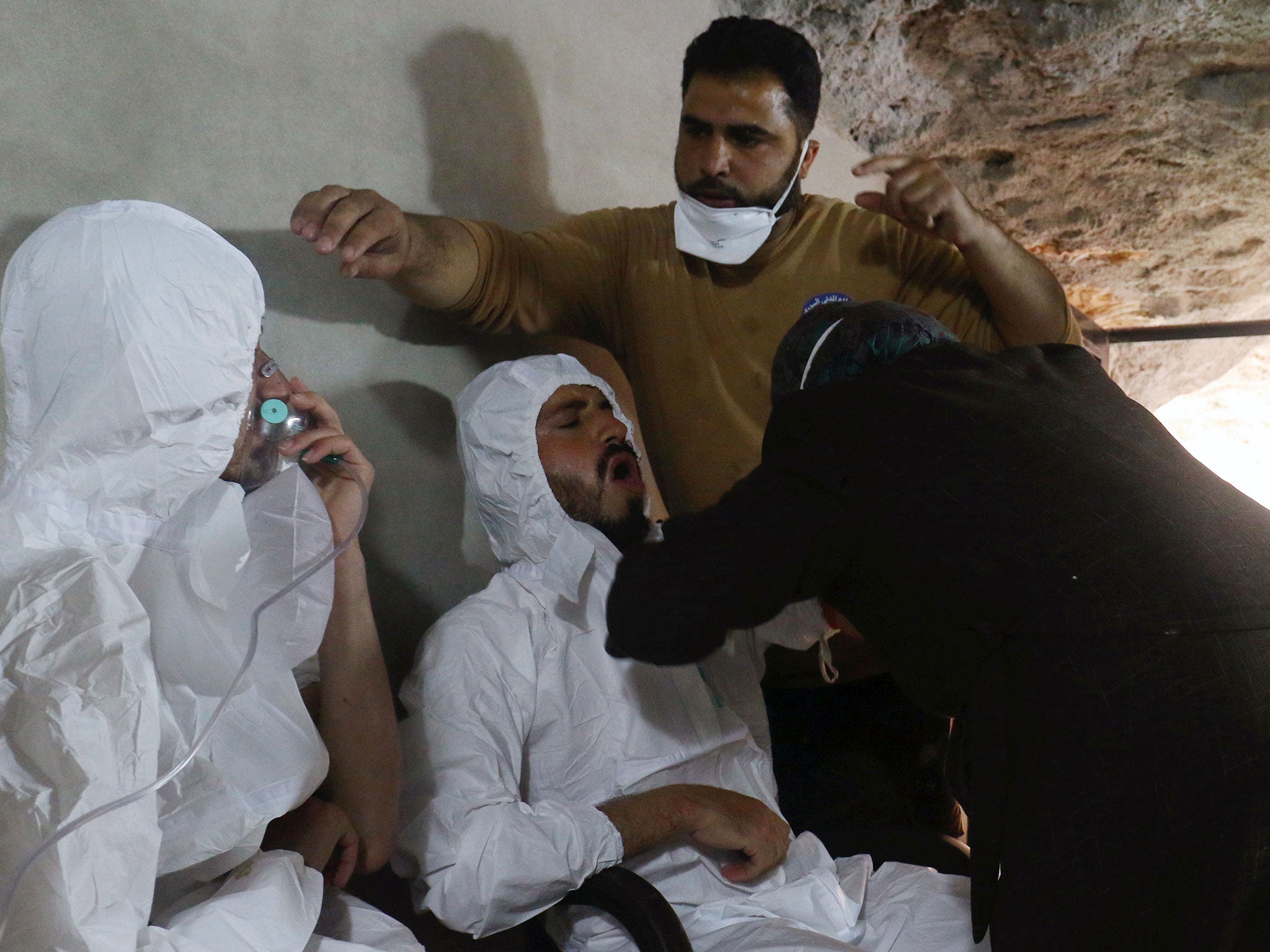 A man breathes through an oxygen mask as another one receives treatment, after what rescue workers described as a suspected gas attack in the town of Khan Sheikhoun on Tuesday