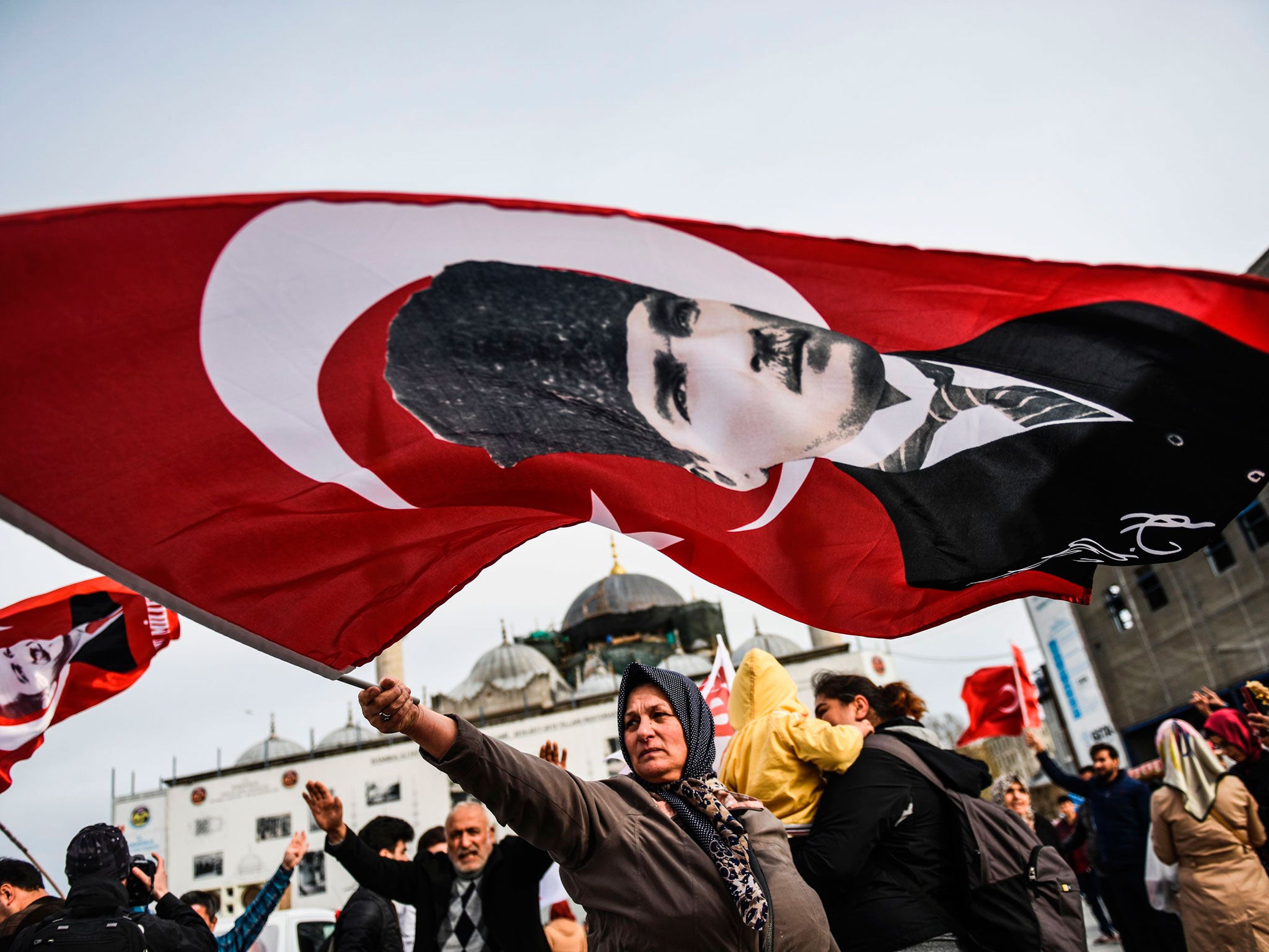 A Turkish woman supporting the 'No' vote in the upcoming constitutional referendum campaign waves a Turkish flag with a picture of modern Turkey's founder Mustafa Kemal Ataturk in front of Yeni Camii