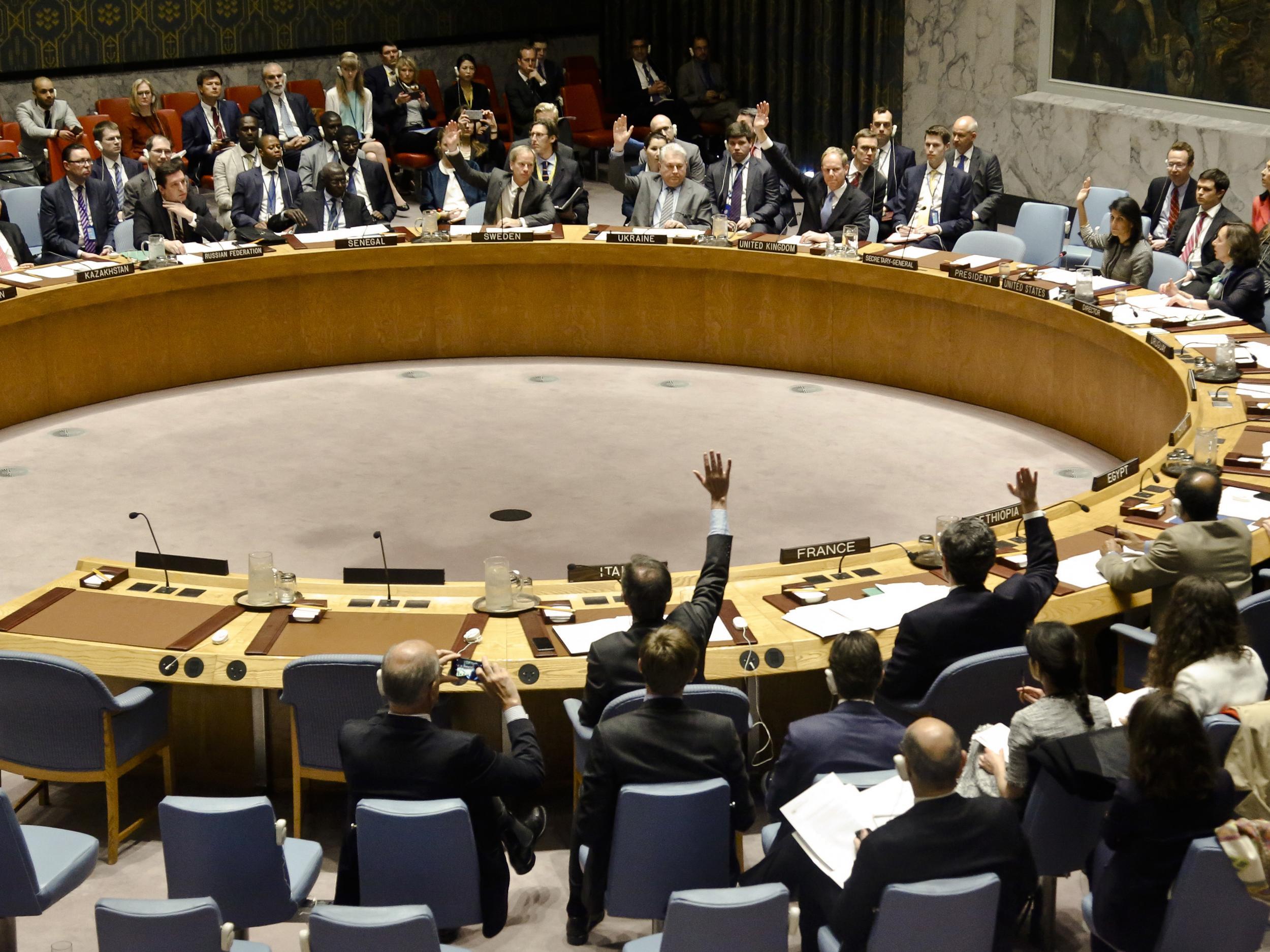 United Nations Security Council members show hands for a vote on a resolution condemning Syria's use of chemical weapons at UN headquarters