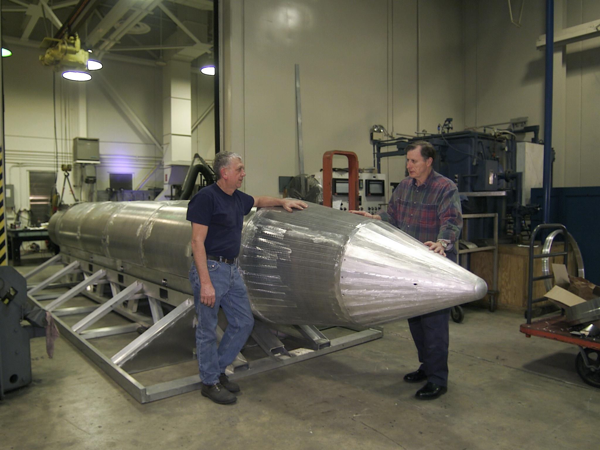 Al Weimorts, the creator of the GBU-43/B Massive Ordnance Air Blast bomb, and Joseph Fellenz, lead model maker, look over the prototype of the bomb before it was painted and tested in March 2003