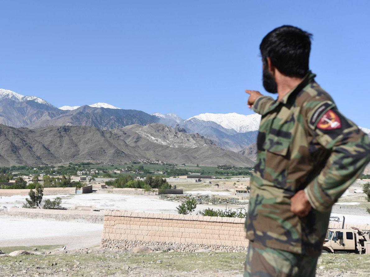 A member of Afghan security points to the mountainous area where the US dropped a MOAB bomb targeting Isis caves in Nangarhar province, Afghanistan