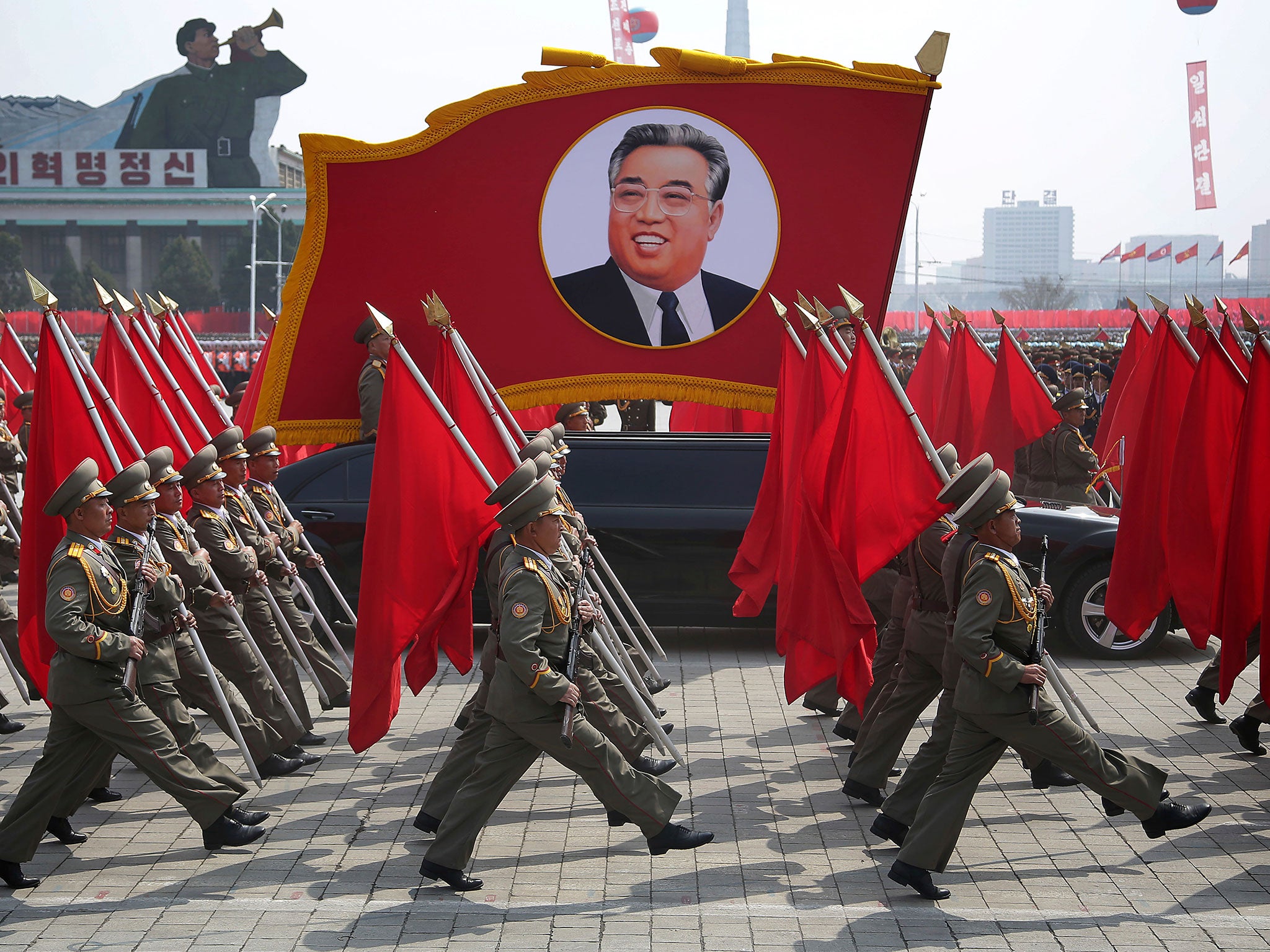 North Korean soldiers carry flags and a photo of Kim Il-sung during a military parade in Pyongyang