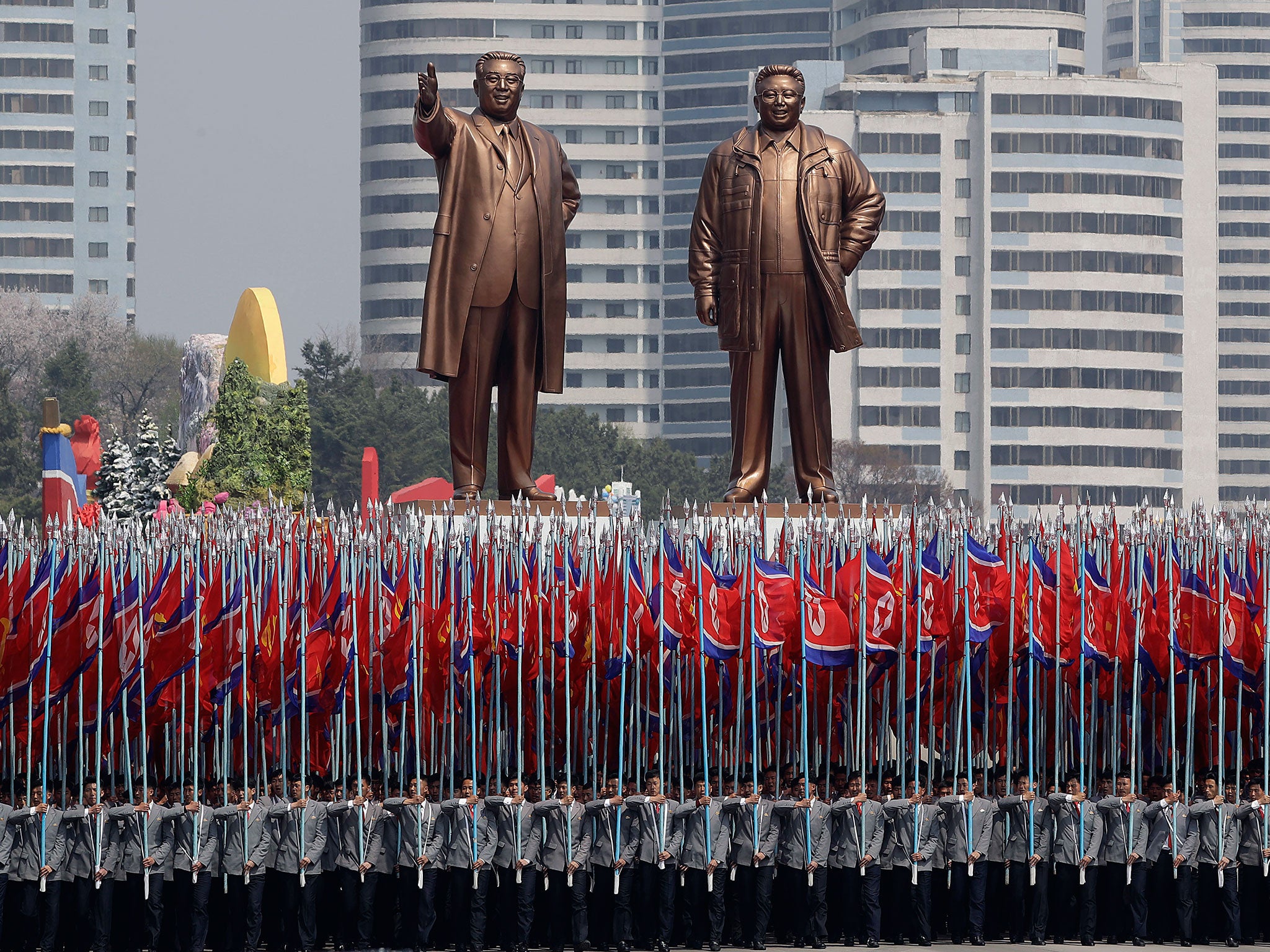 University students carry the national flag and two bronze statues of late leaders Kim Il-sung and Kim Jong-il