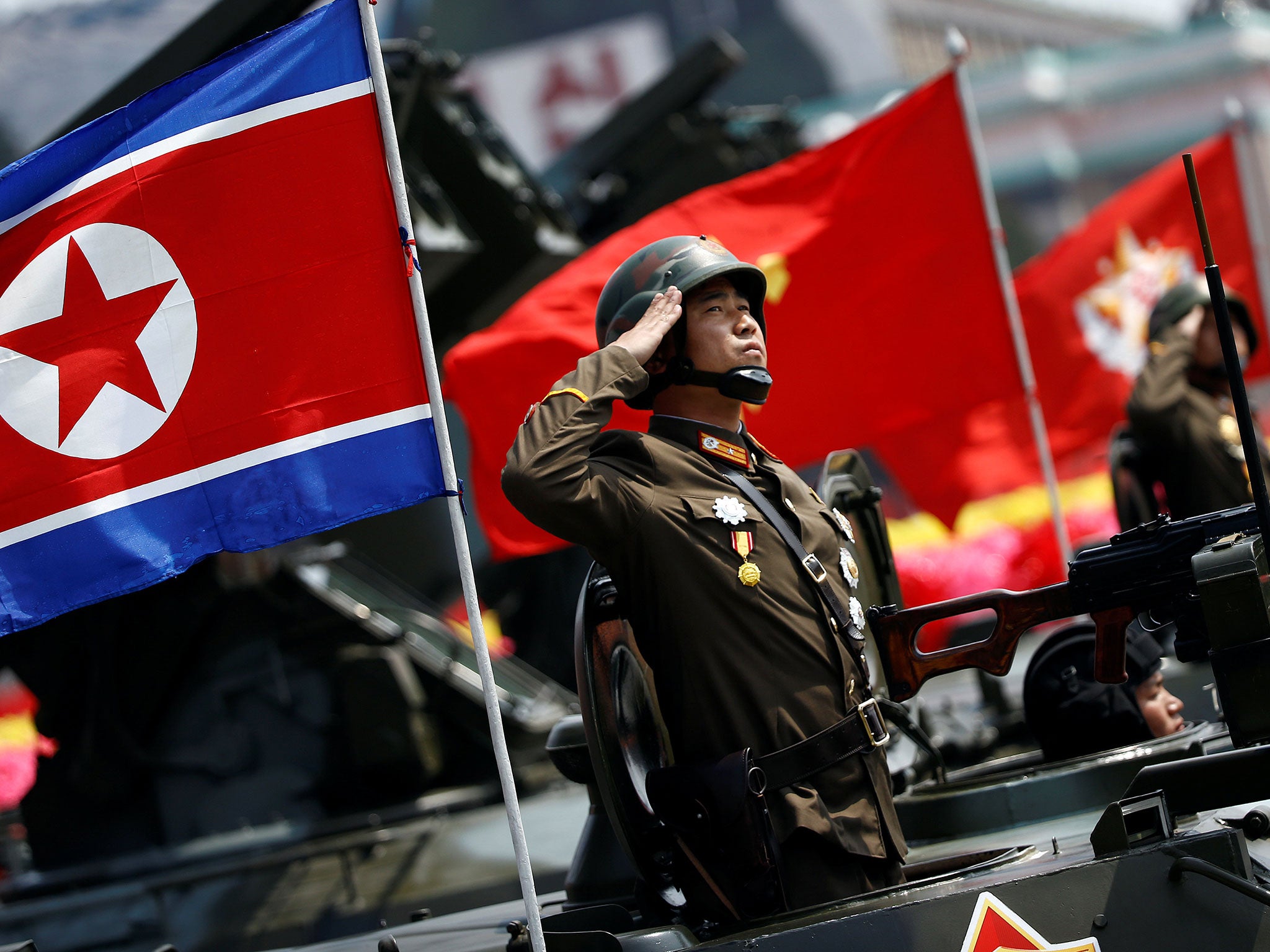 A soldier salutes from atop an armoured vehicle during a parade