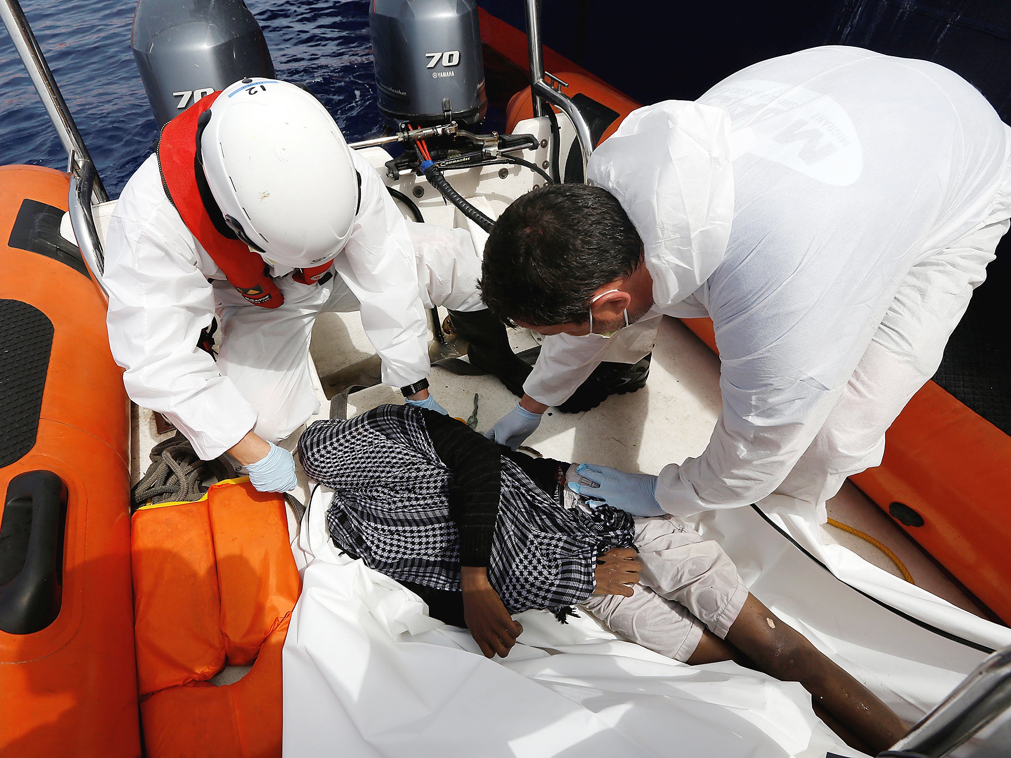 Rescuers place a dead migrant into a body bag after some 20 migrants drowned in international waters off the coast of Libya