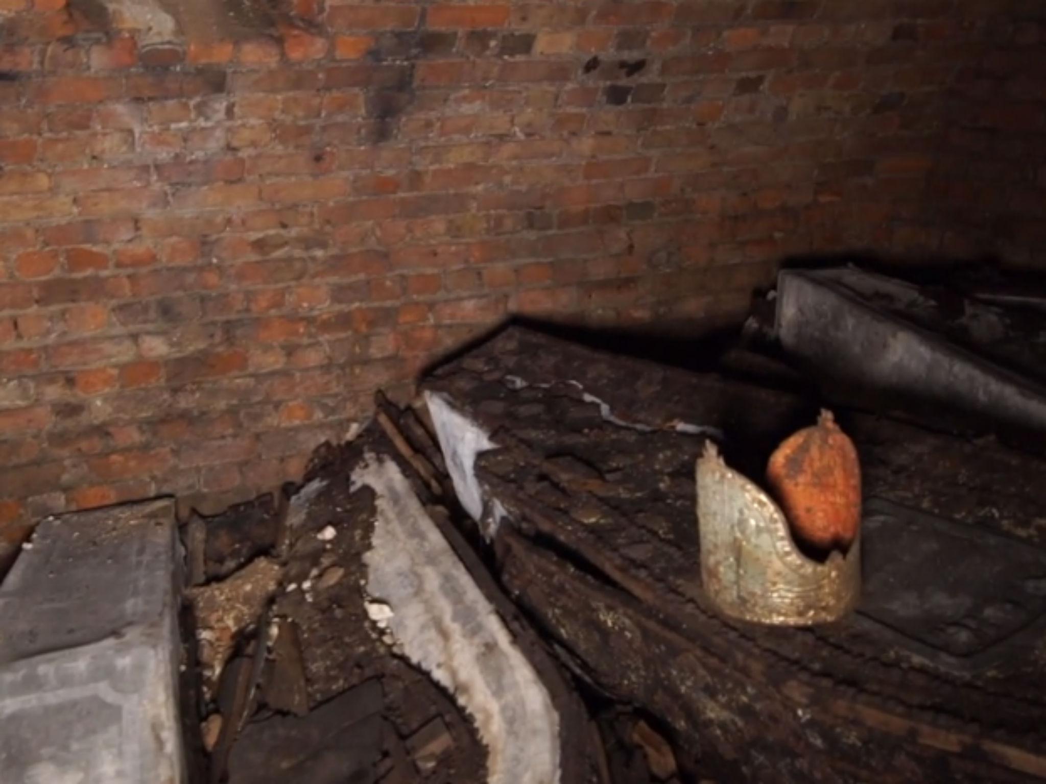 A red and gold mitre sits atop the pile of coffins