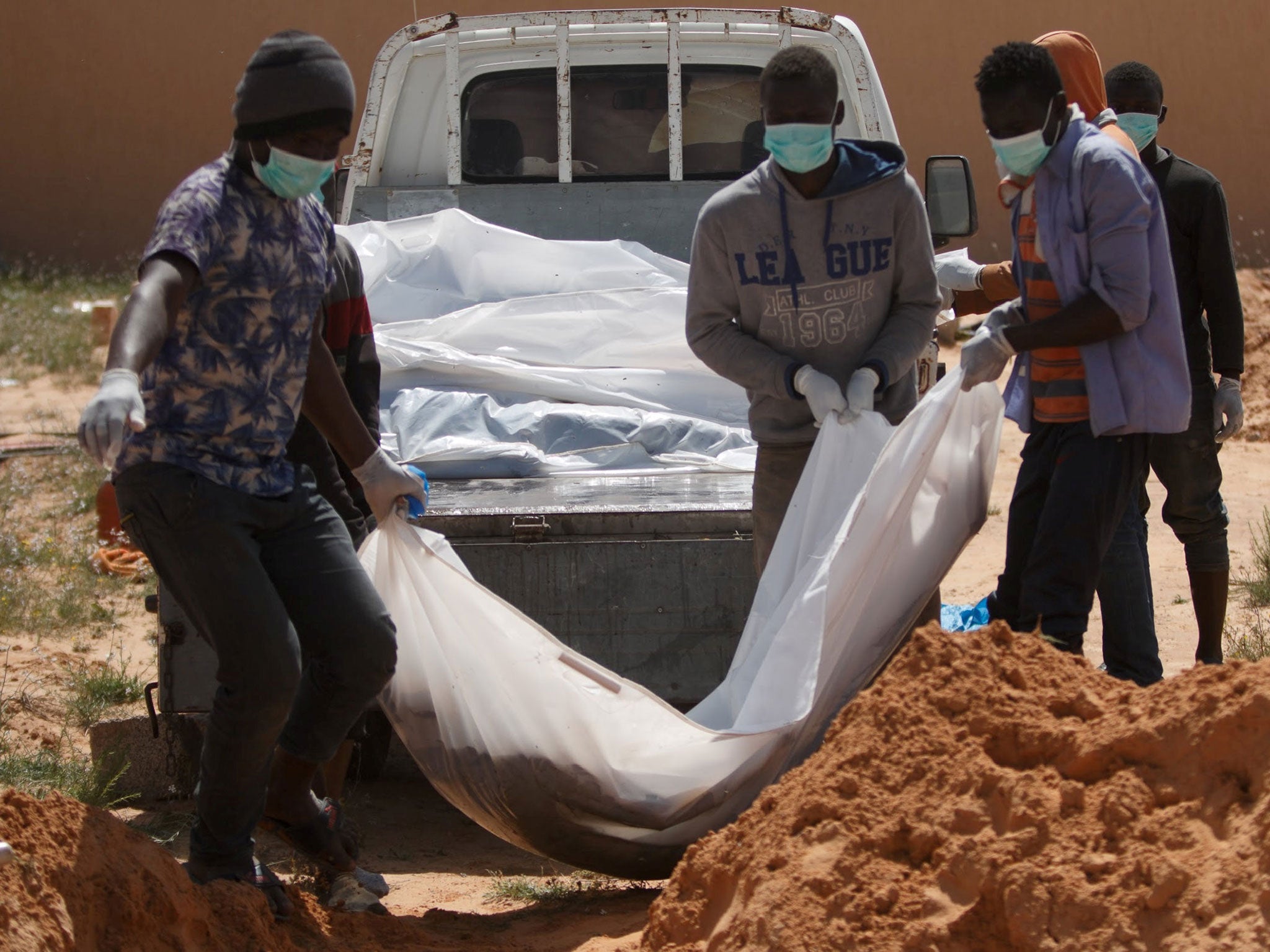 Men carry bags containing dead bodies of migrants as they bury them in a cemetery fin Sabratha, Libya, on 18 April