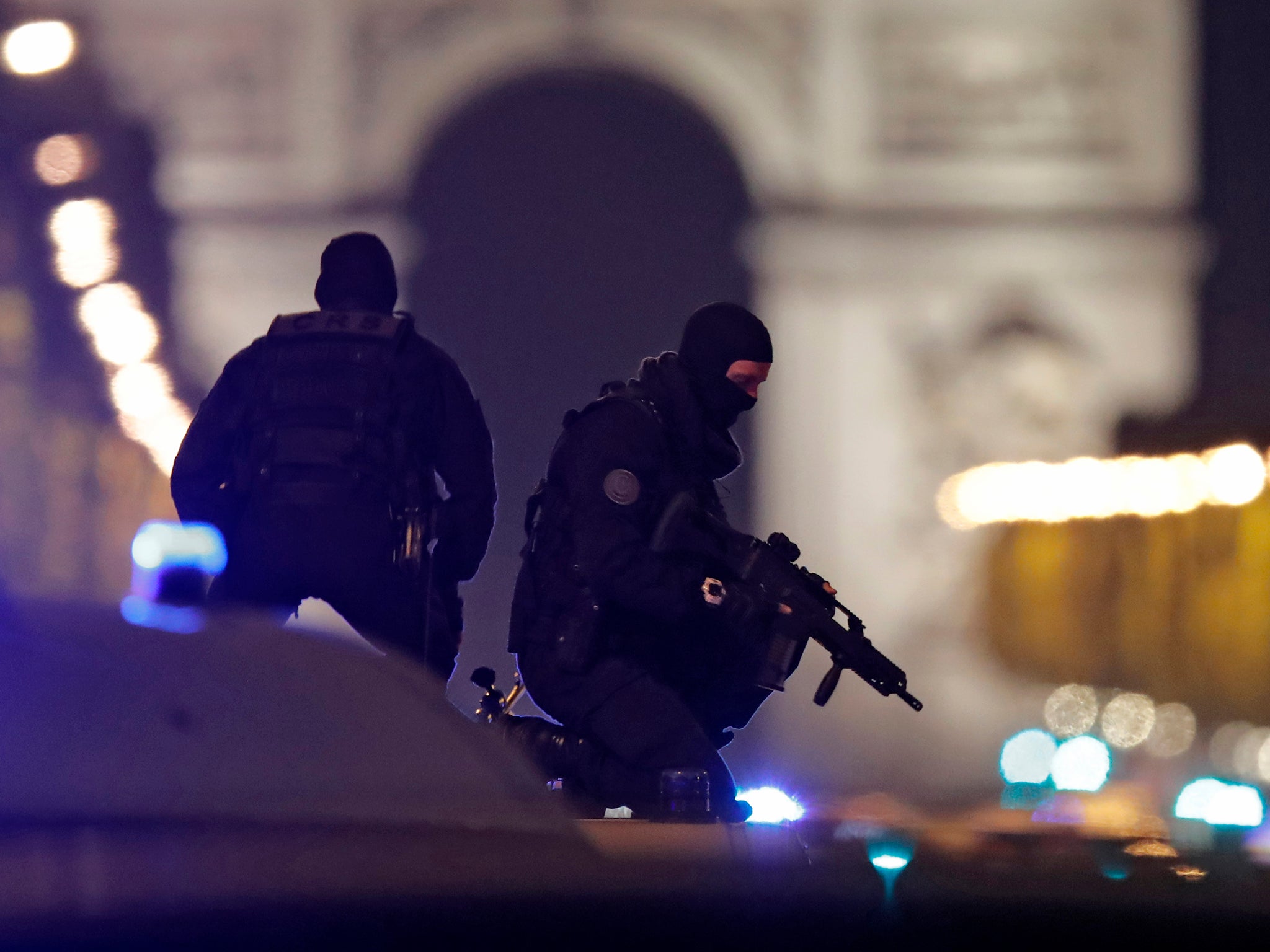 Masked police stand on top of their vehicle on the Champs-Elysees after a police officer was killed and two were injured