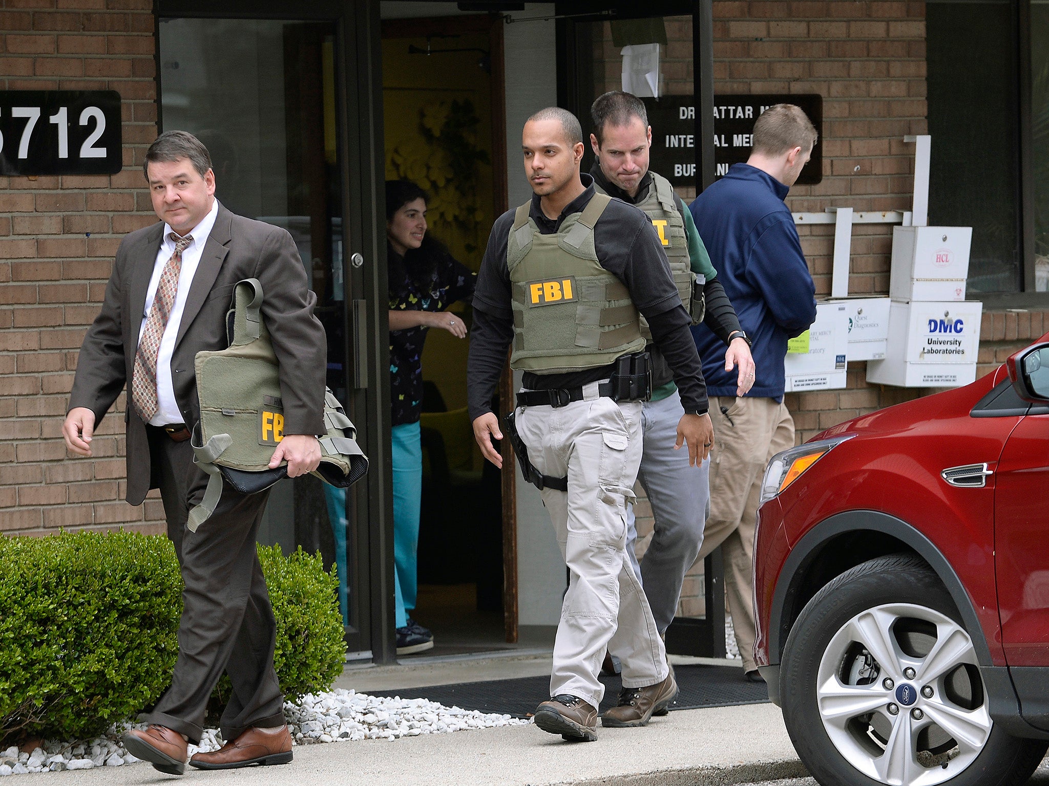 FBI agents leave the office of Dr Fakhruddin Attar at the Burhani Clinic in Livonia after searching for documents