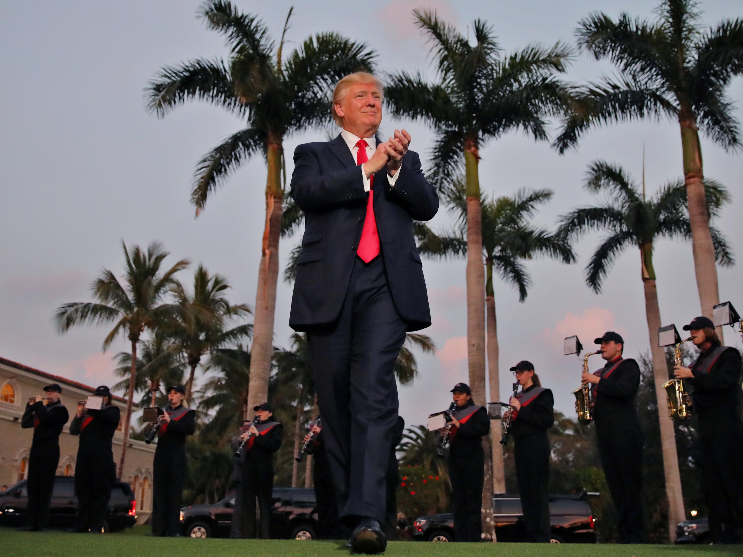 President Trump applauds a marching band at the Trump International Golf Club in West Palm Beach, Florida