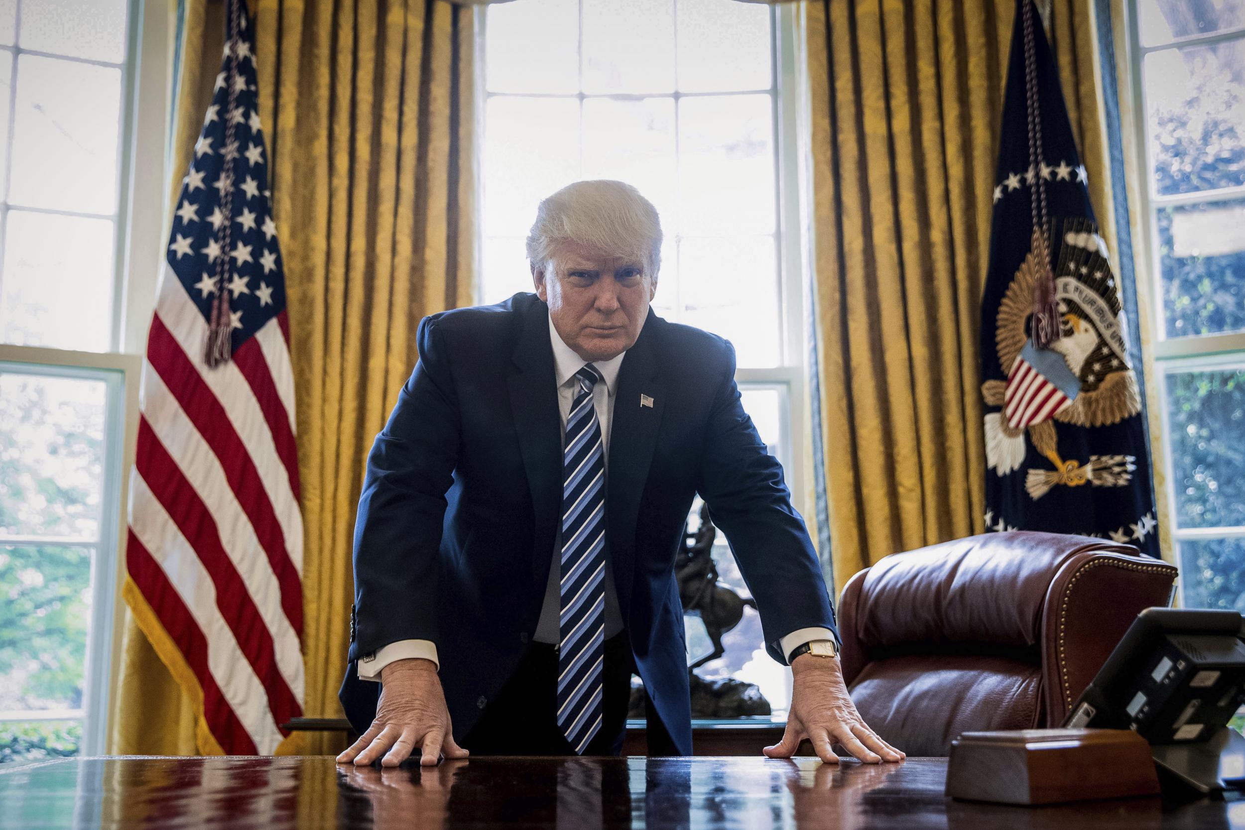 President Donald Trump poses for a portrait in the Oval Office