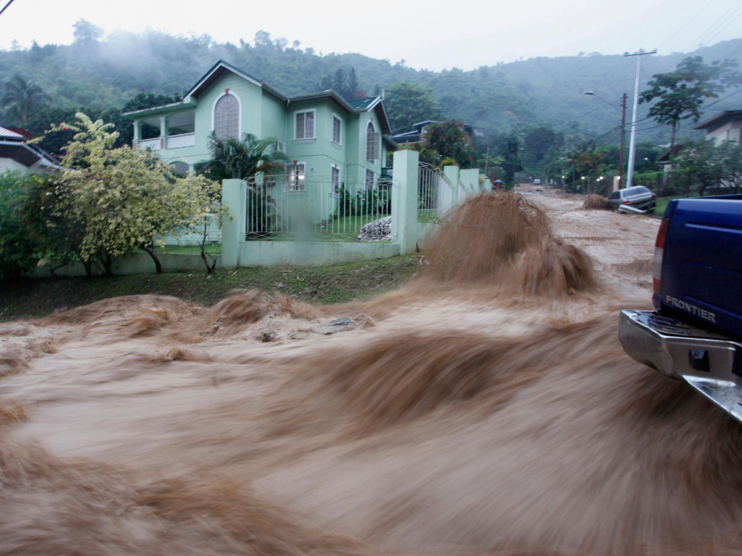 A torrent of water water rushes past a vehicle at Westvale Park, Glencoe, near Port-of-Spain in Trinidad