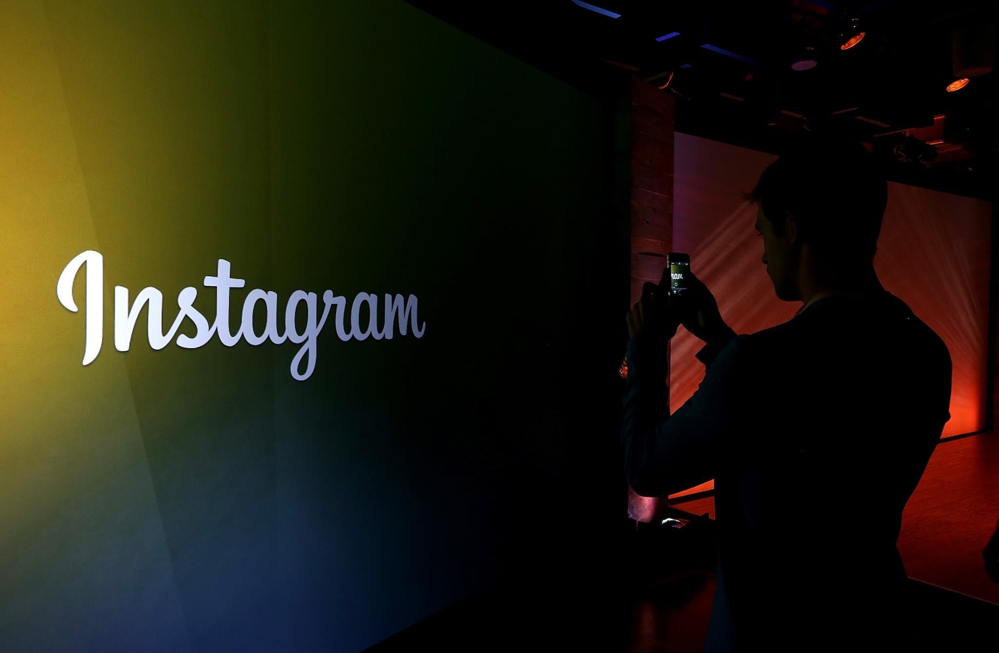 An attendee takes a photo of the instagram logo during a press event at Facebook headquarters on June 20, 2013 in Menlo Park, California