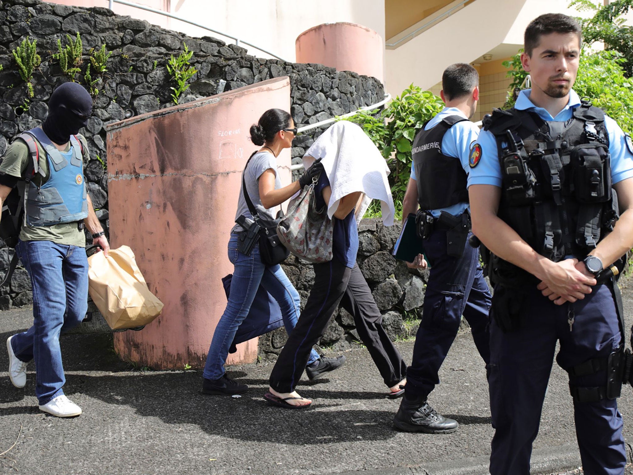 French gendarmes and police officers escort a person on the French island of Reunion, after a man suspected of being a radicalised Islamist shot two officers on 27 April