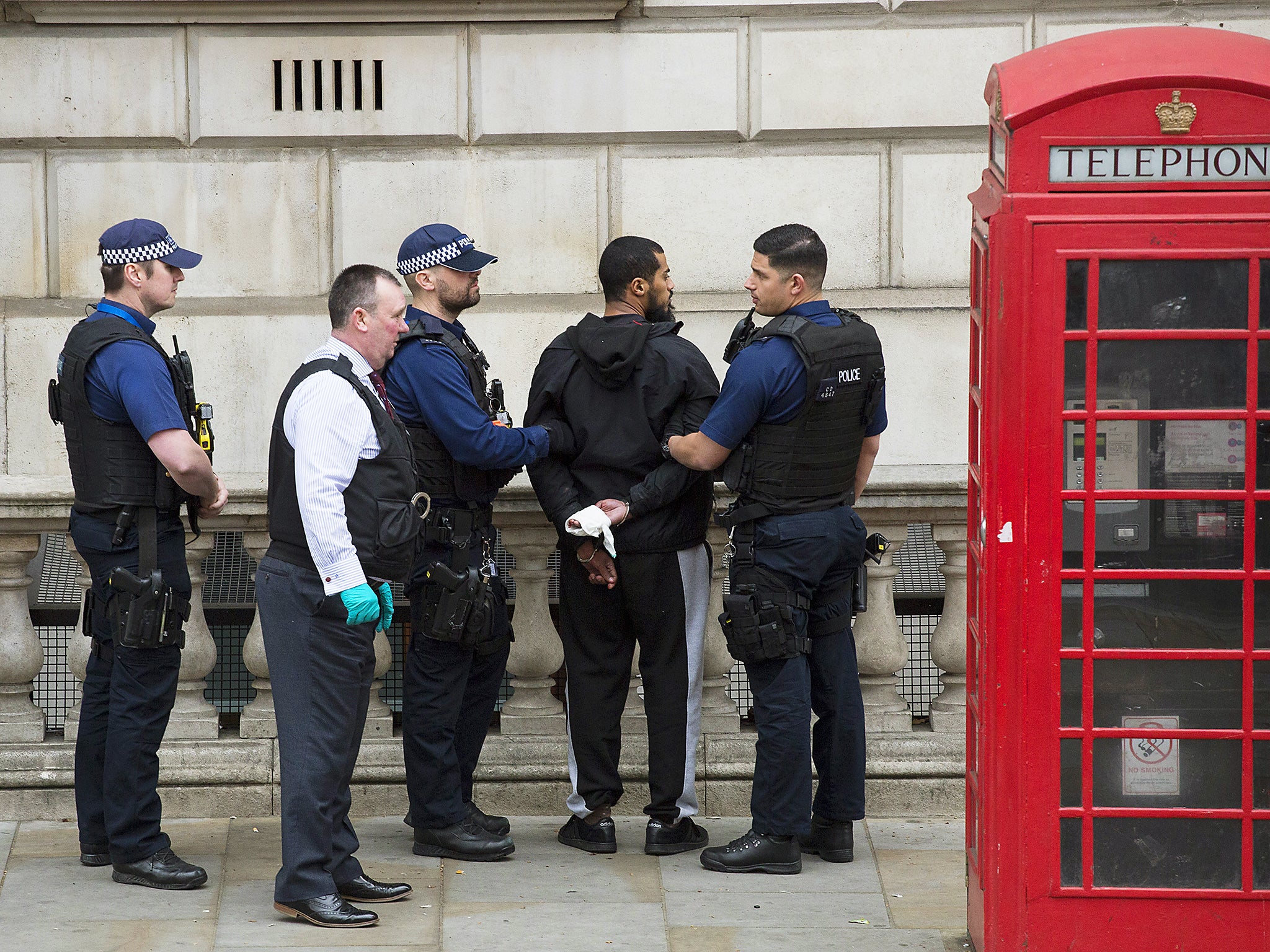 A man is detained by police officers near Downing Street