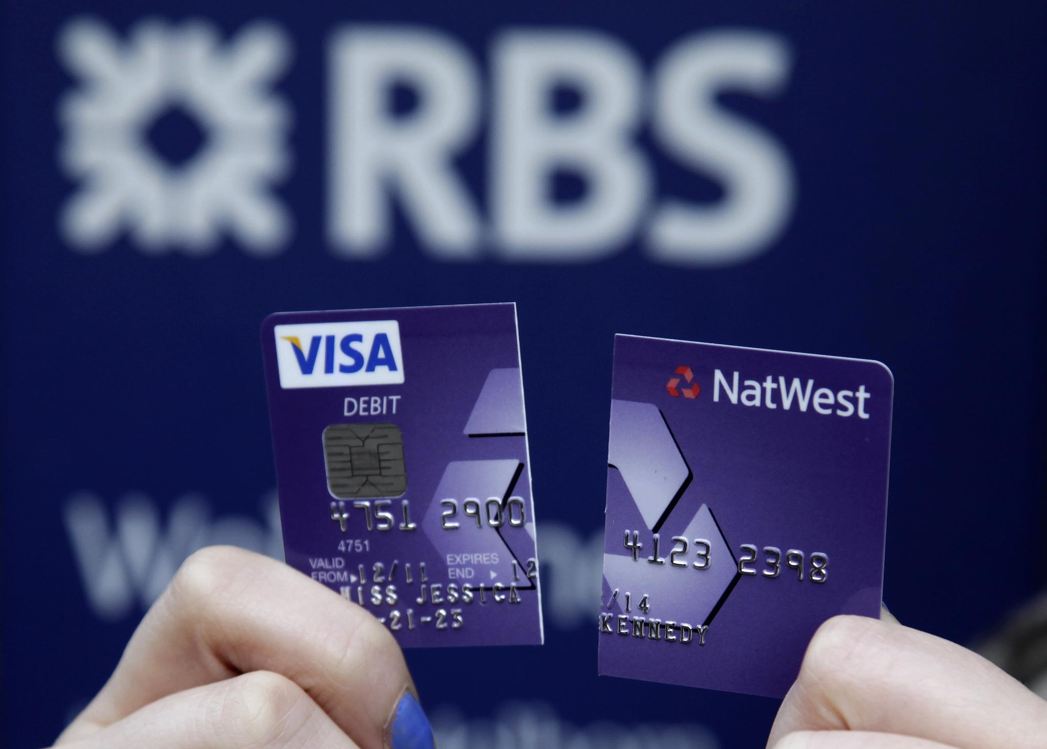 A demonstrator holds up her destroyed NatWest debit card as she stands in front of a branch of the Royal Bank of Scotland (RBS) in London February 23, 2012