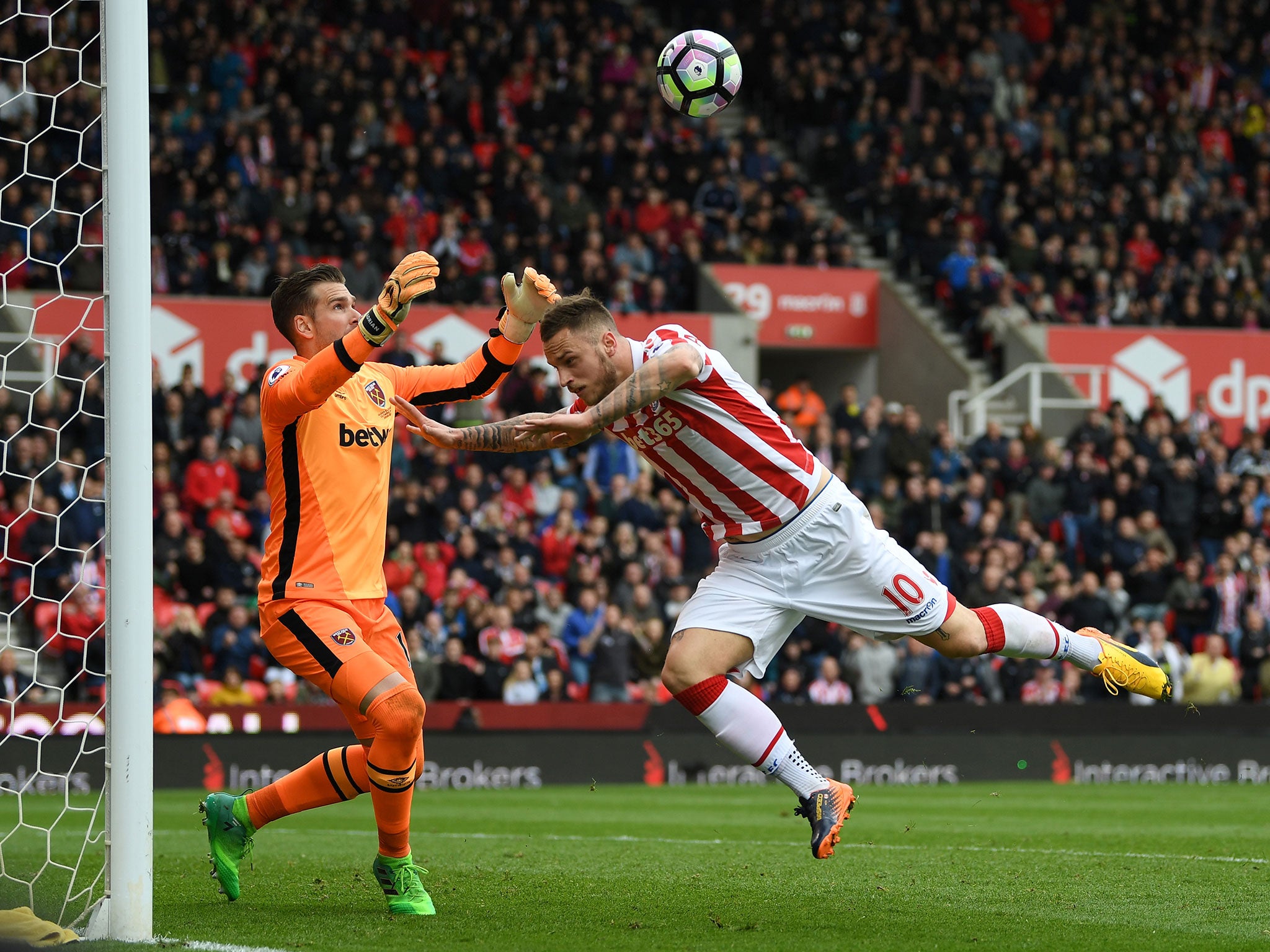 Adrian punches the ball clear under pressure from Marko Arnautovic