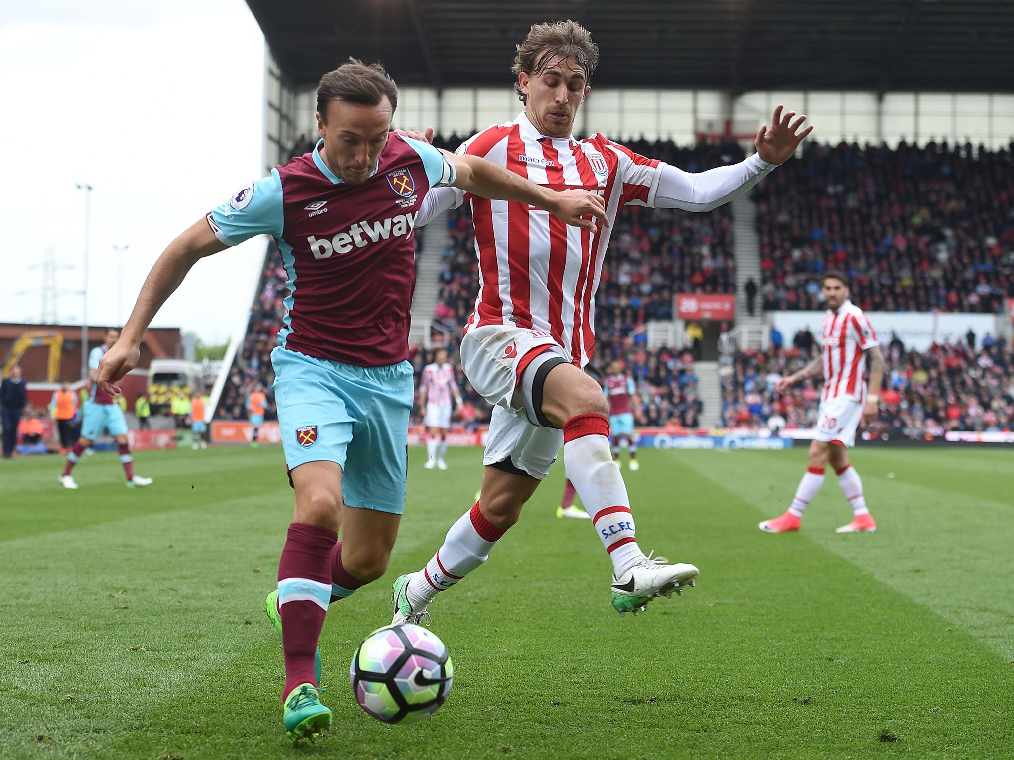 Mark Noble clears the ball under pressure from Marc Muniesa