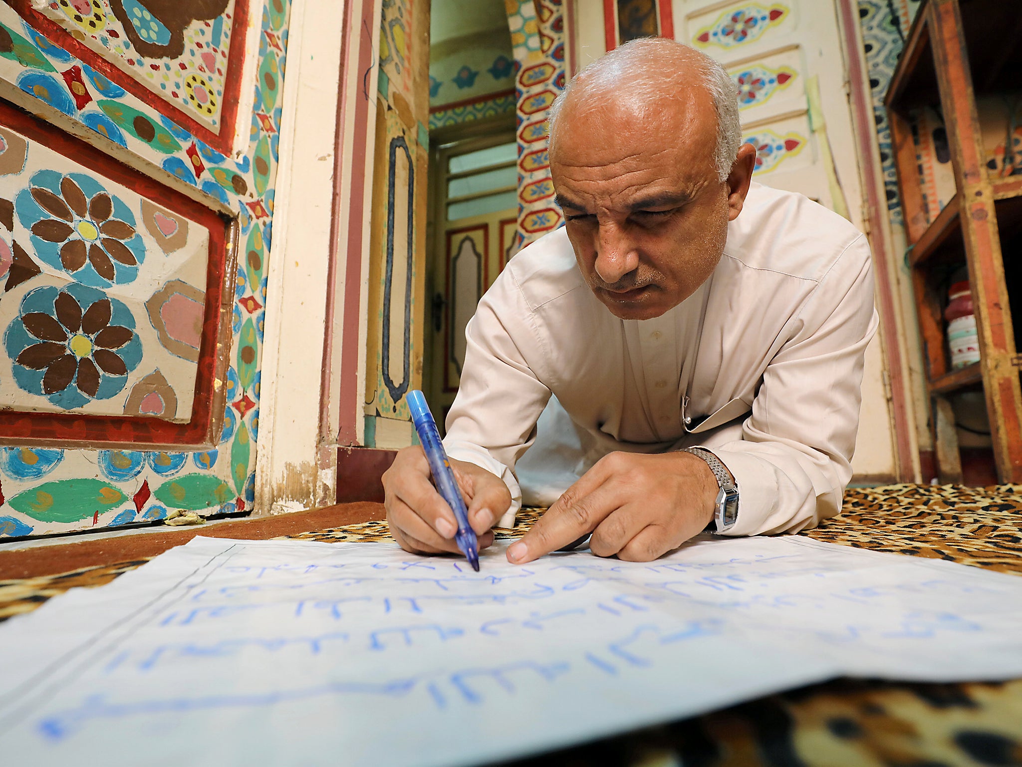 &#13;
Saad Mohammed writes as he sits on the floor of his studio &#13;