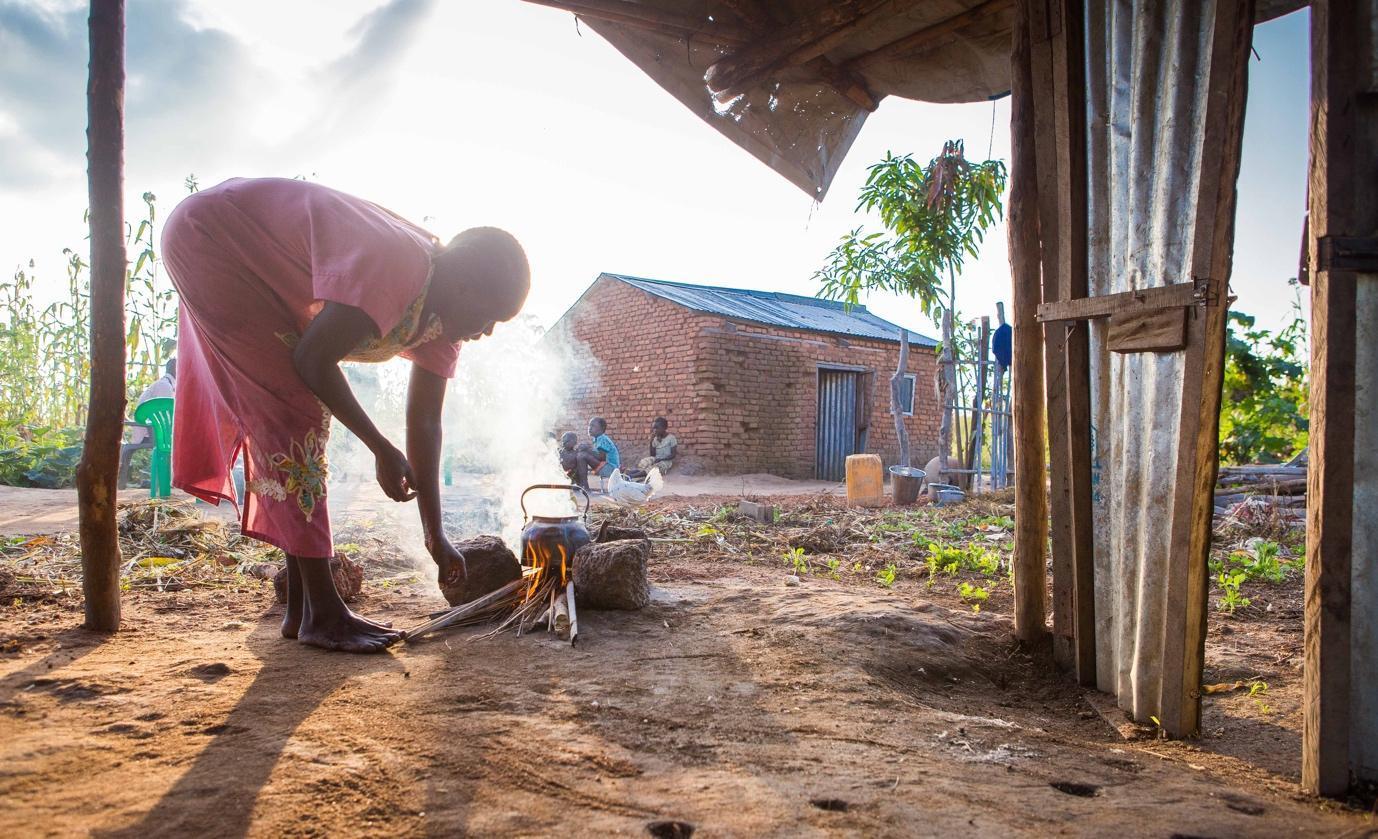 Veronica in South Sudan preparing tea outside her home, recently ravaged by heavy flooding