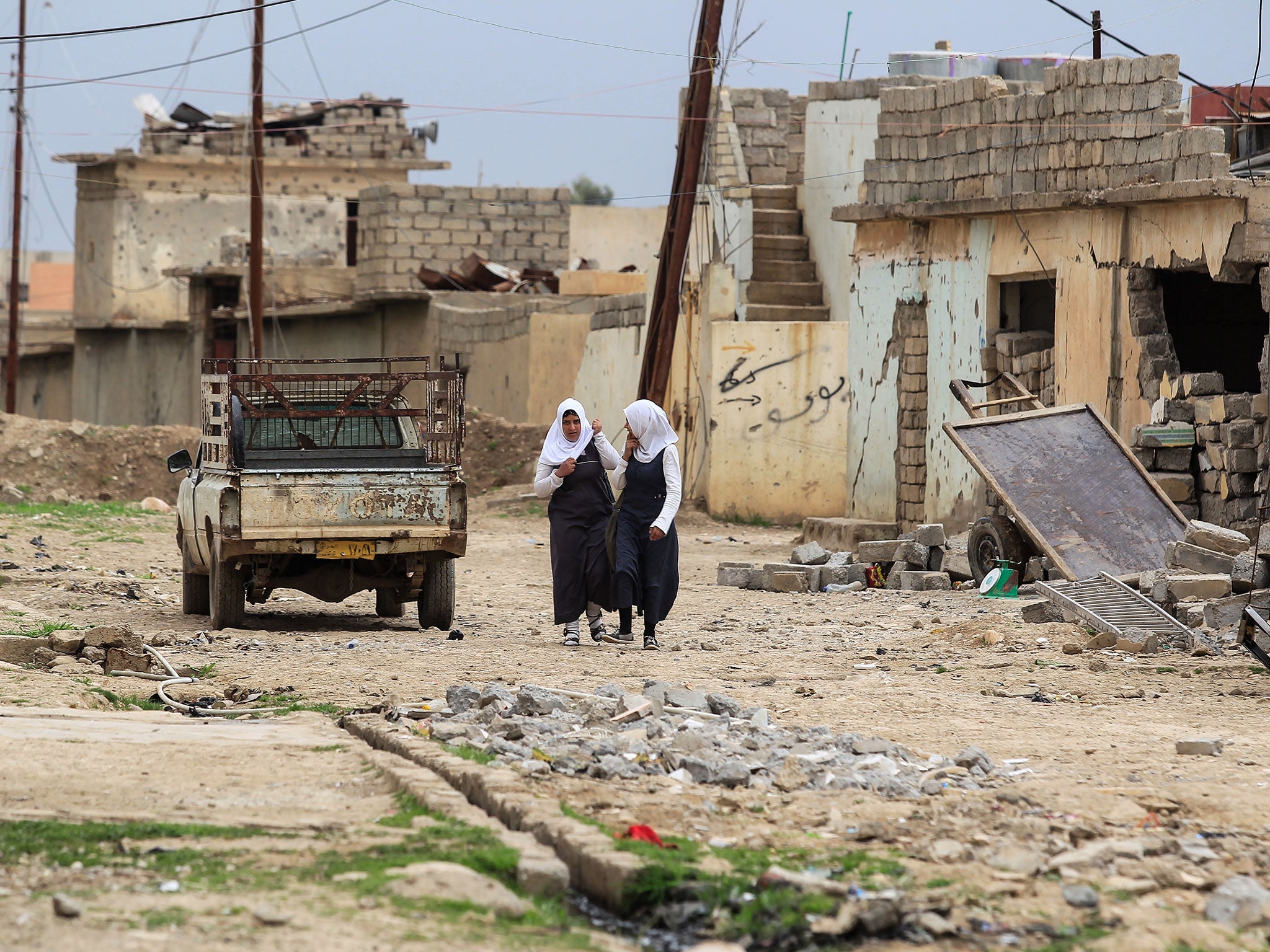 Girls walking through destroyed buildings in Tel Kaif, near Mosul