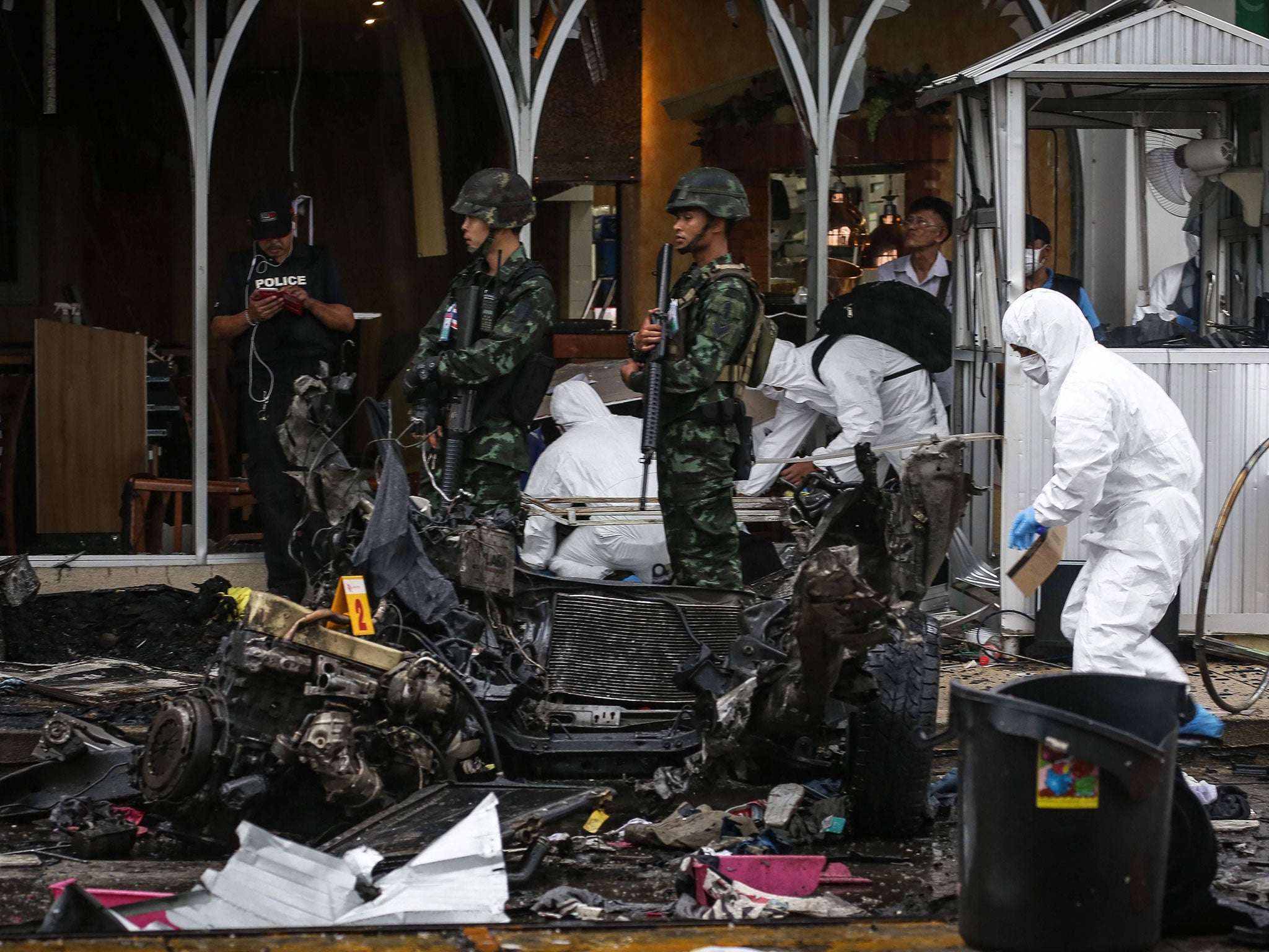 Thai soldiers stand guard as a forensics unit inspects the aftermath of a car bomb in front of Big C in the town centre of Pattani on 9 May