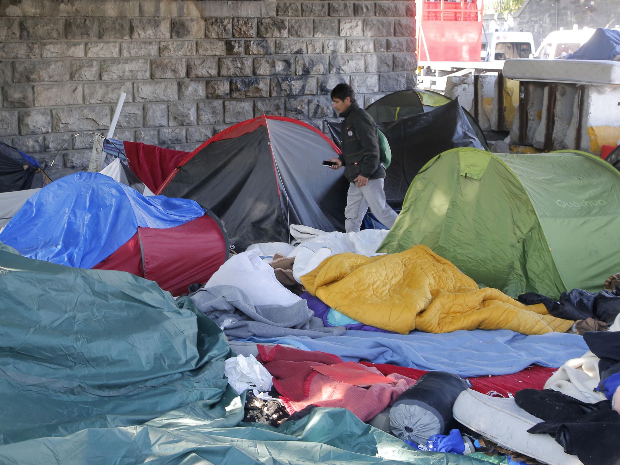 An afghan refugee walks through an evacuated makeshift camp after Paris police have evacuated more than 1,000 migrants living in squalid conditions in the French capital