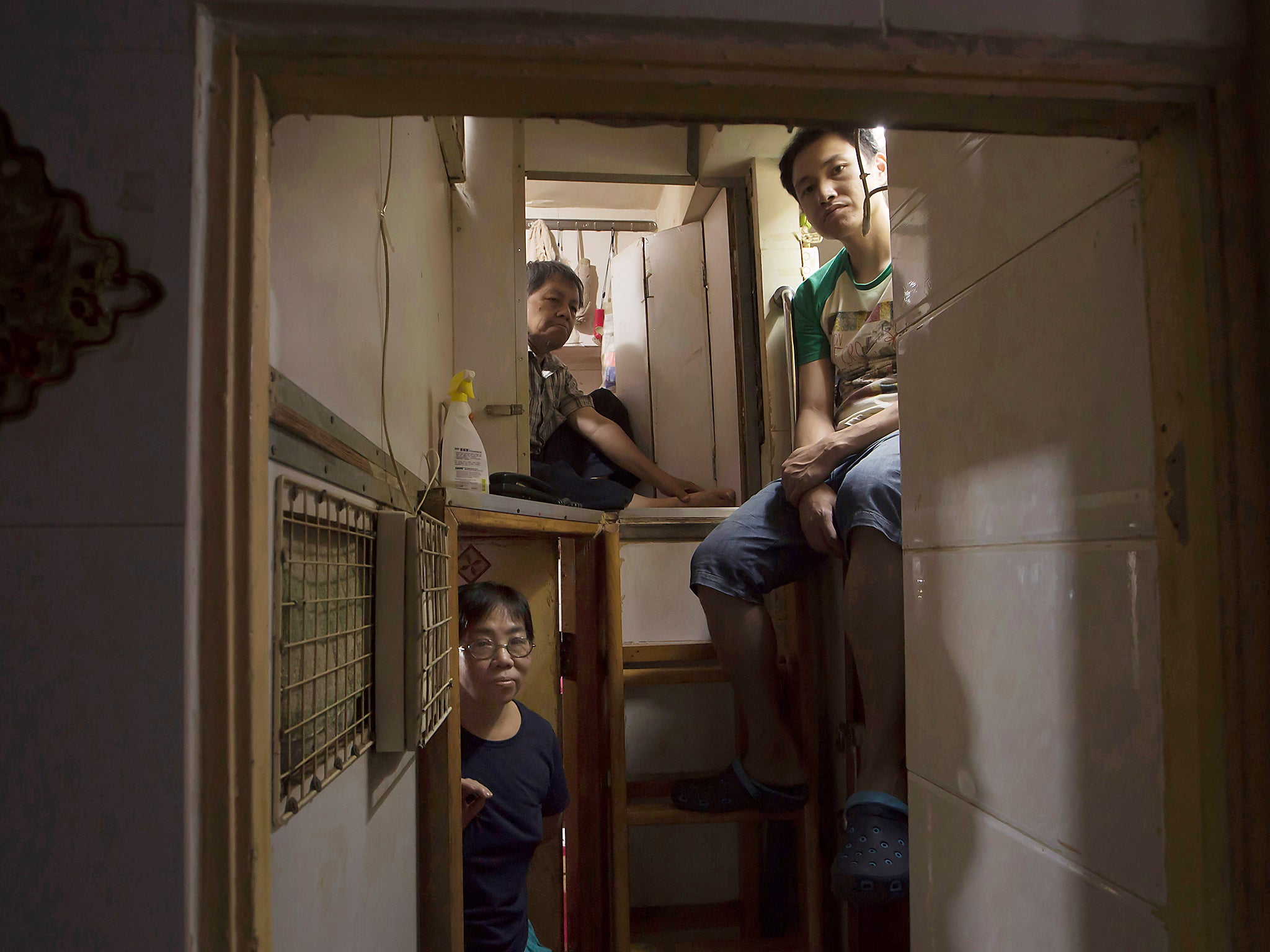 Hong Kong residents, who only gave their surname, Lam, top left, Wan, top right, and Kitty Au, pose at their 'coffin homes' in Hong Kong