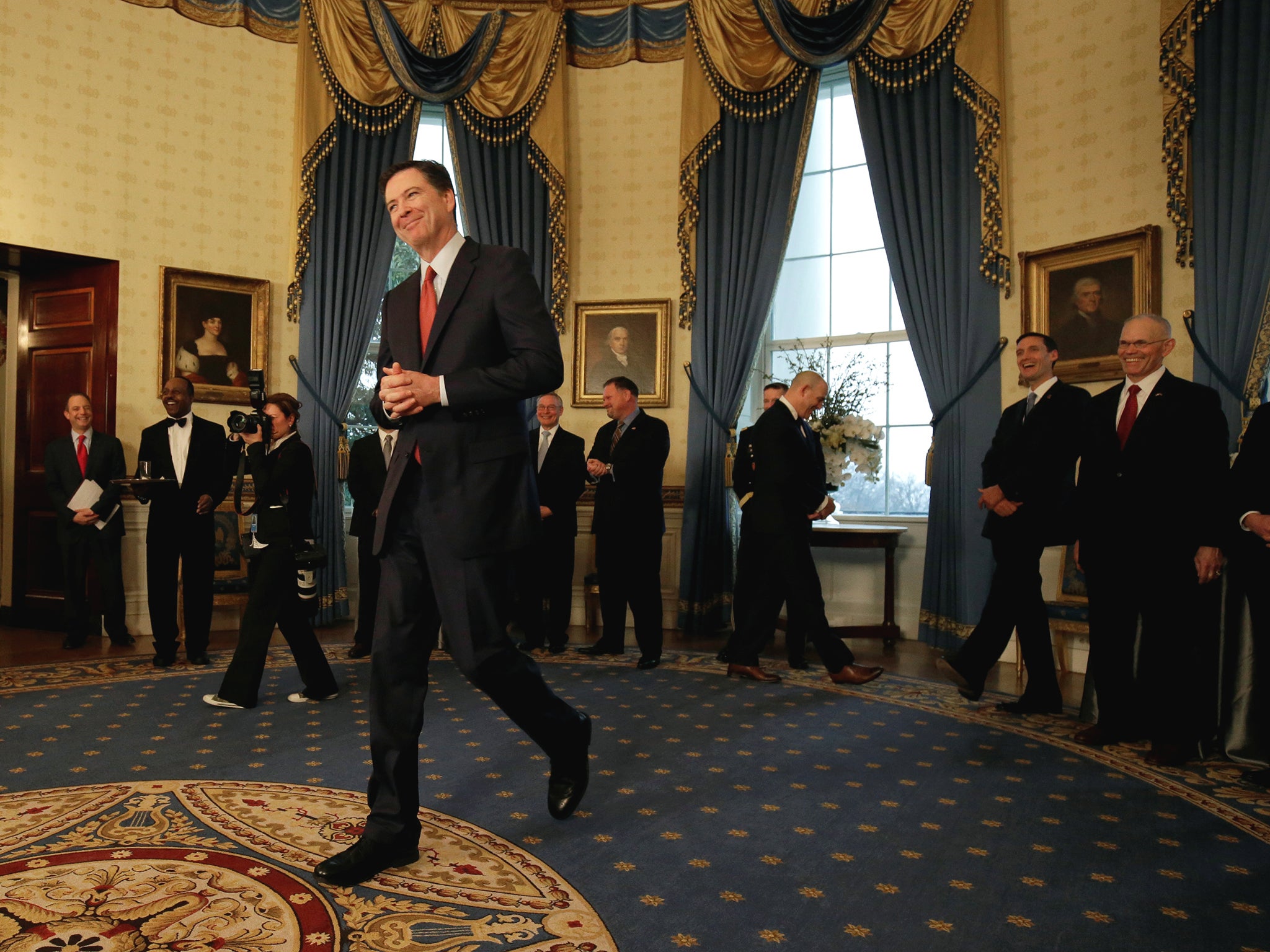 Director of the FBI James Comey walks to greet US President Donald Trump during the Inaugural Law Enforcement Officers and First Responders Reception in the Blue Room of the White House