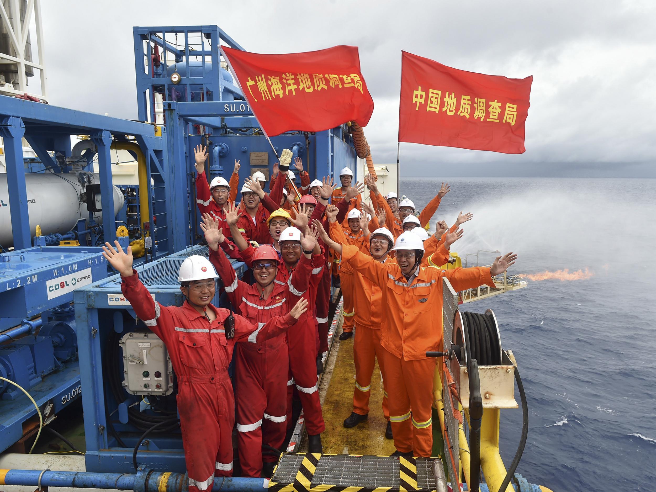 Workers celebrate the successful trial extraction of natural gas from combustible ice trapped under the seafloor on a drilling platform on the South China Sea