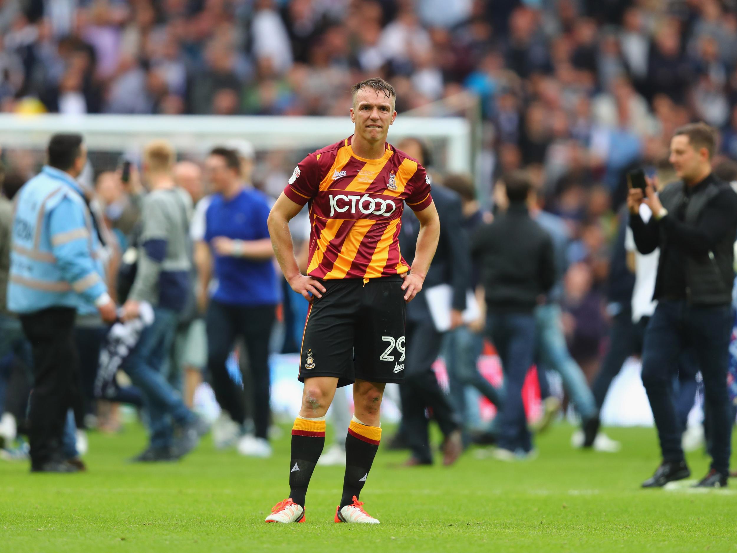 Anthony McMahon stands dejected as Millwall fans invade the pitch