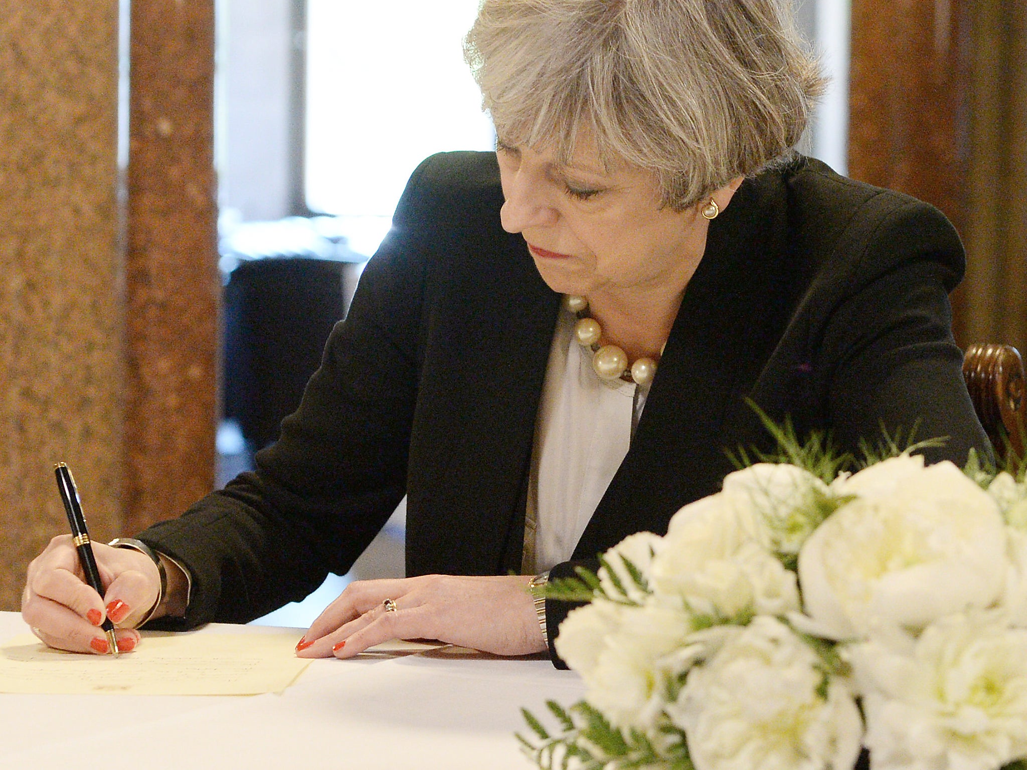 Britain's Prime Minister Theresa May writes a message for the book of condolences for the victims of the attack on Manchester Arena, at Manchester Town Hall in Manchester