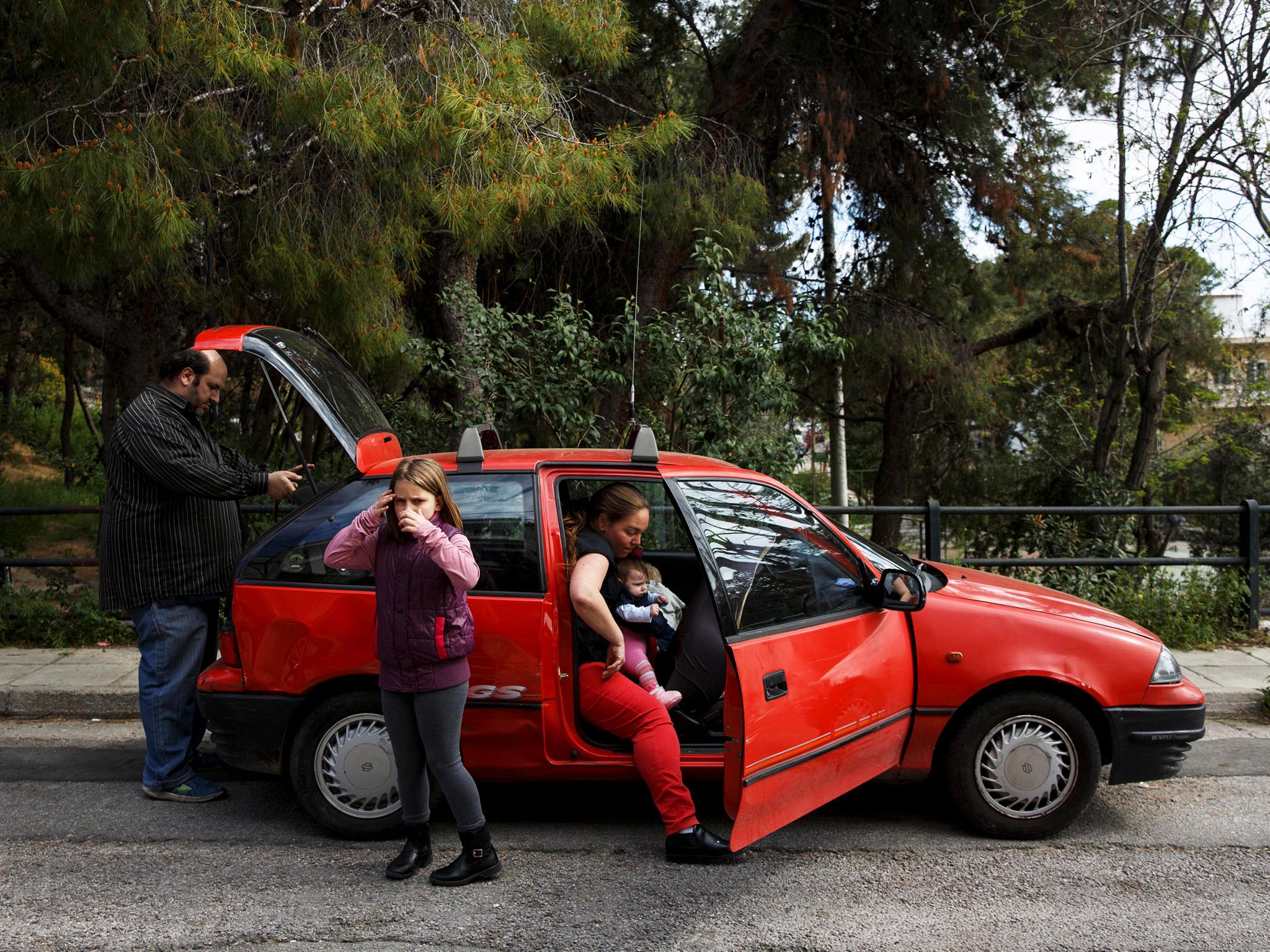 The Argyros family get into their car, which was donated, after receiving goods from Theofilos, an NGO for big families in Athens, Greece