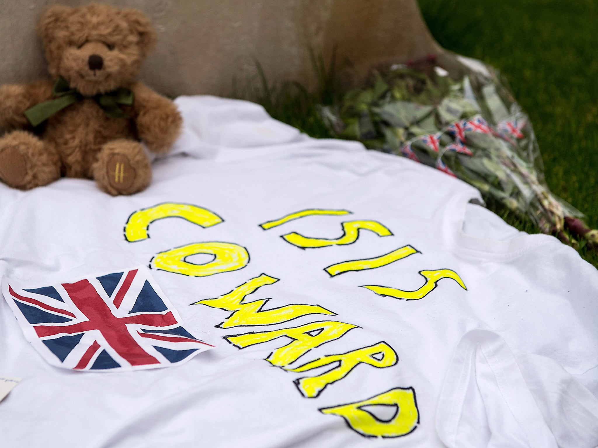 A message reading 'ISIS Coward' is pictured alongside a teddy bear and flowers in Albert Square in Manchester, northwest England