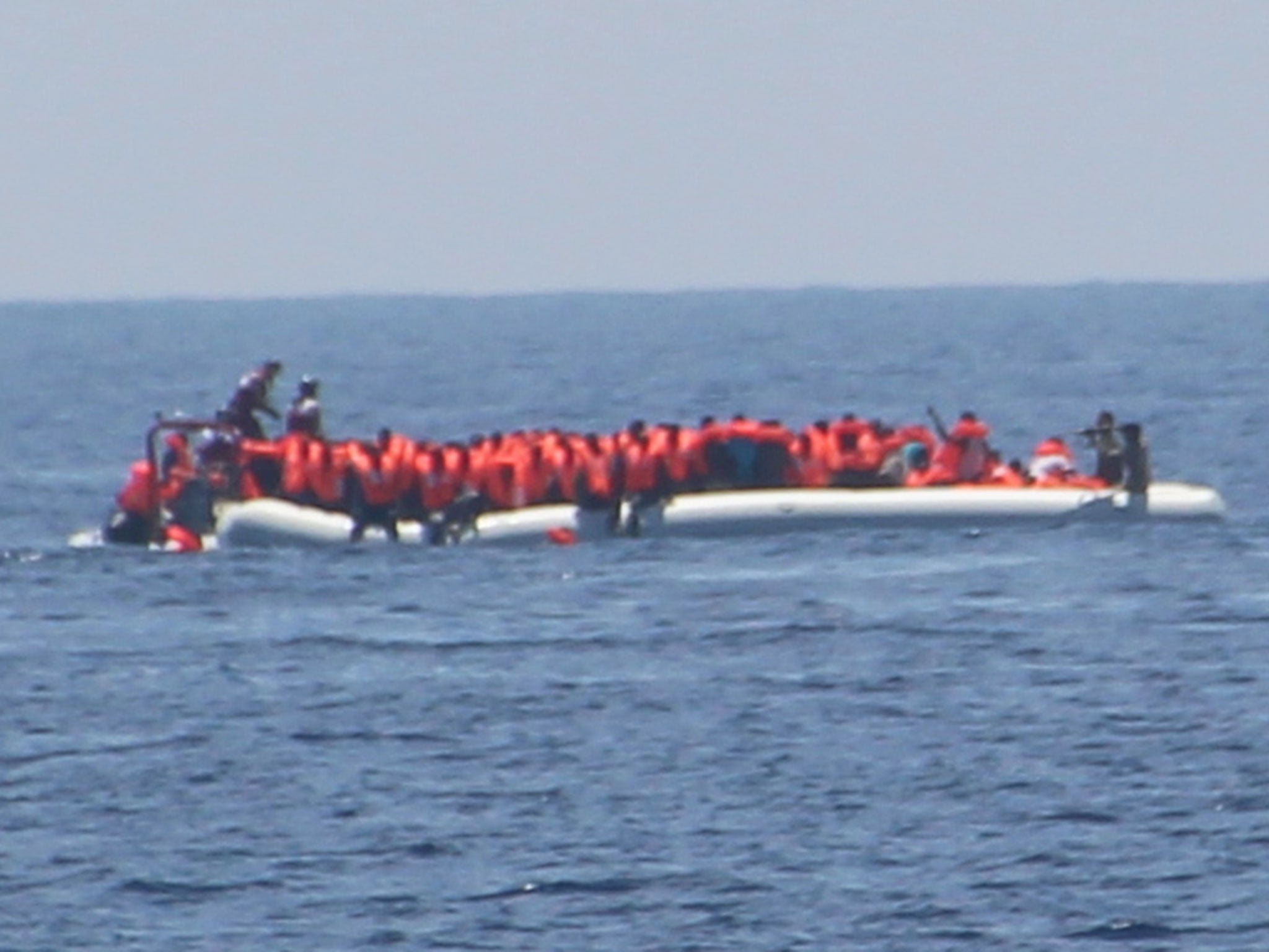 The crew of Jugend Rettet's Iuventa rescue ship photographed what appears to be a Libyan coastguard officer pointing a weapon at refugees (far right)