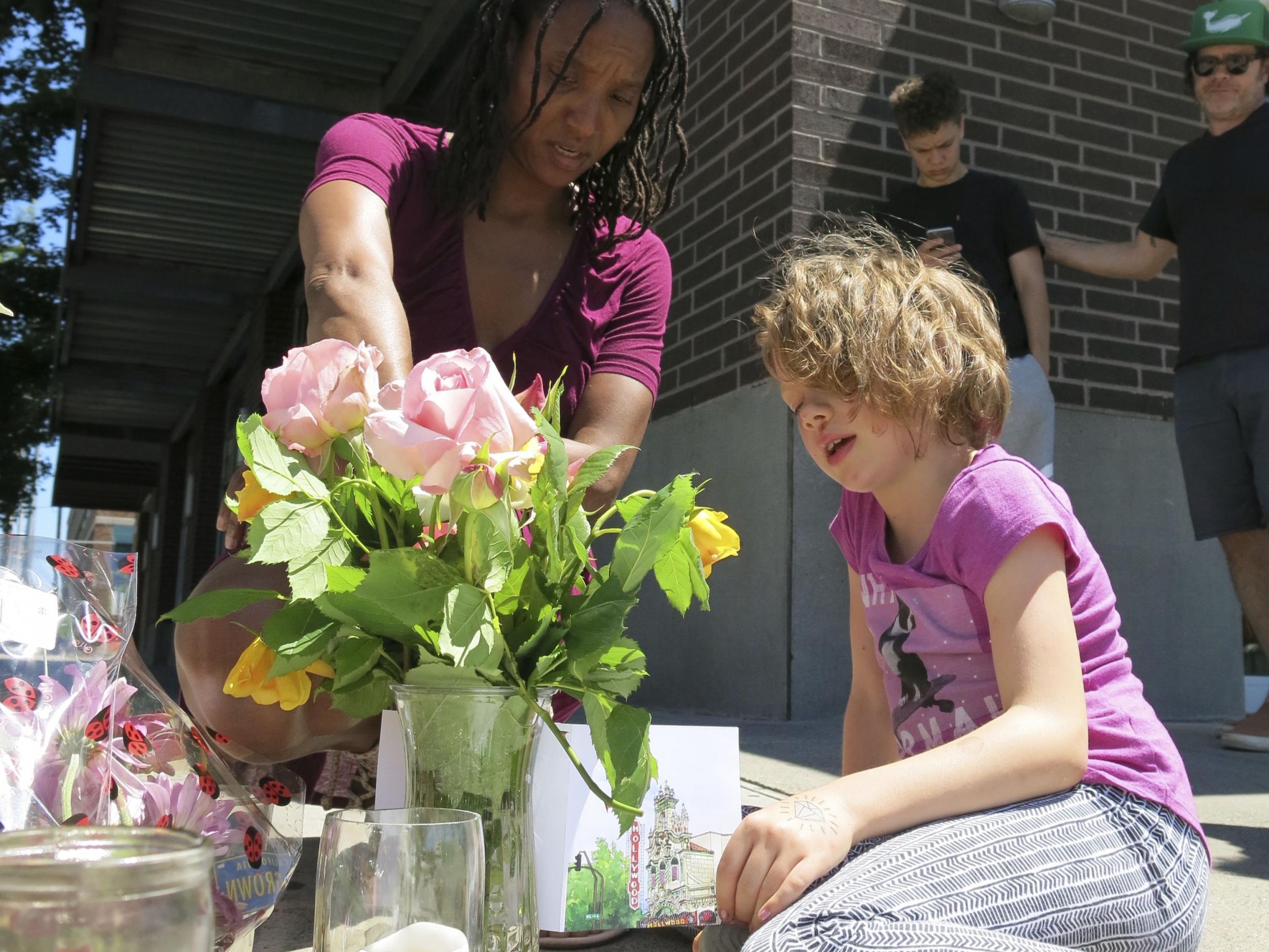 Angel Sauls, left, helps her stepdaughter Coco Douglas arrange a sign and some painted rocks she made for a memorial in Portland, Oregon, in memory of the two bystanders who were stabbed to death on Friday while trying to stop a man who was yelling anti-Muslim slurs and acting aggressively toward two young women