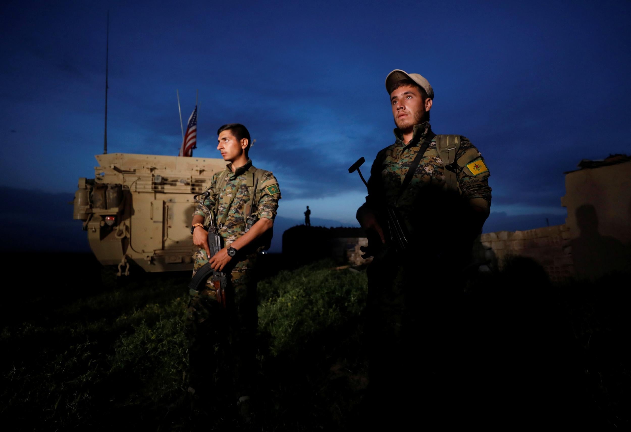 Kurdish fighters from the People's Protection Units (YPG) stand near a US military vehicle in the town of Darbasiya next to the Turkish border, Syria, on 28 April 28 2017