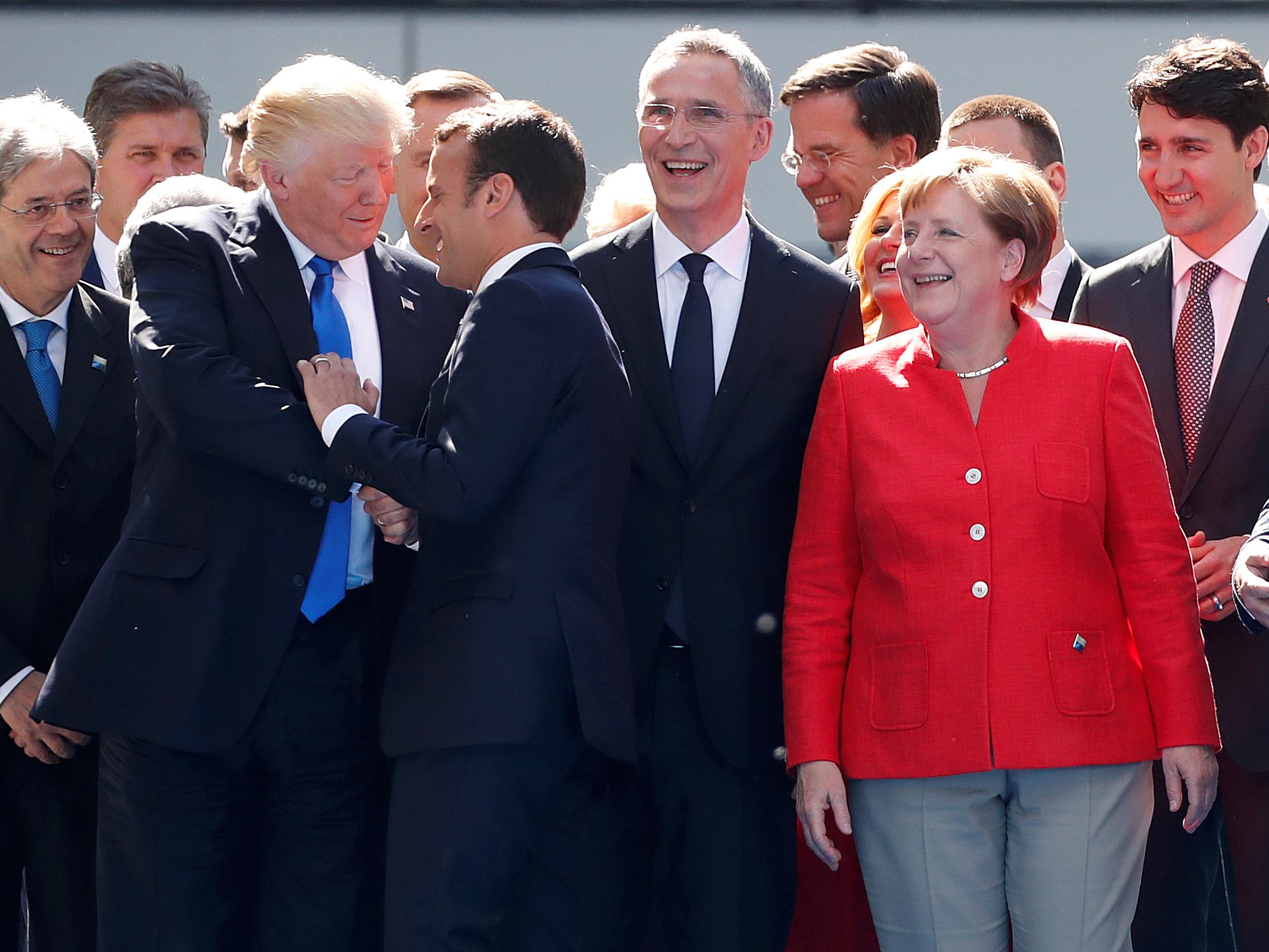 US President Donald Trump shakes hands with French President Emmanuel Macron as German Chancellor Angela Merkel laughs with fellow Nato leaders