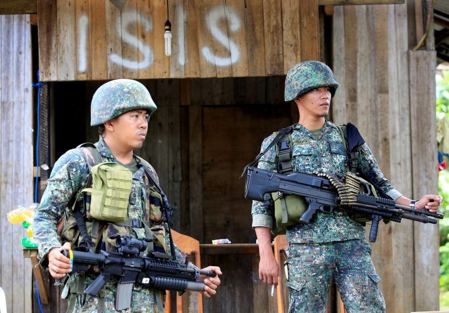 Soldiers stand guard along the main street of Mapandi village