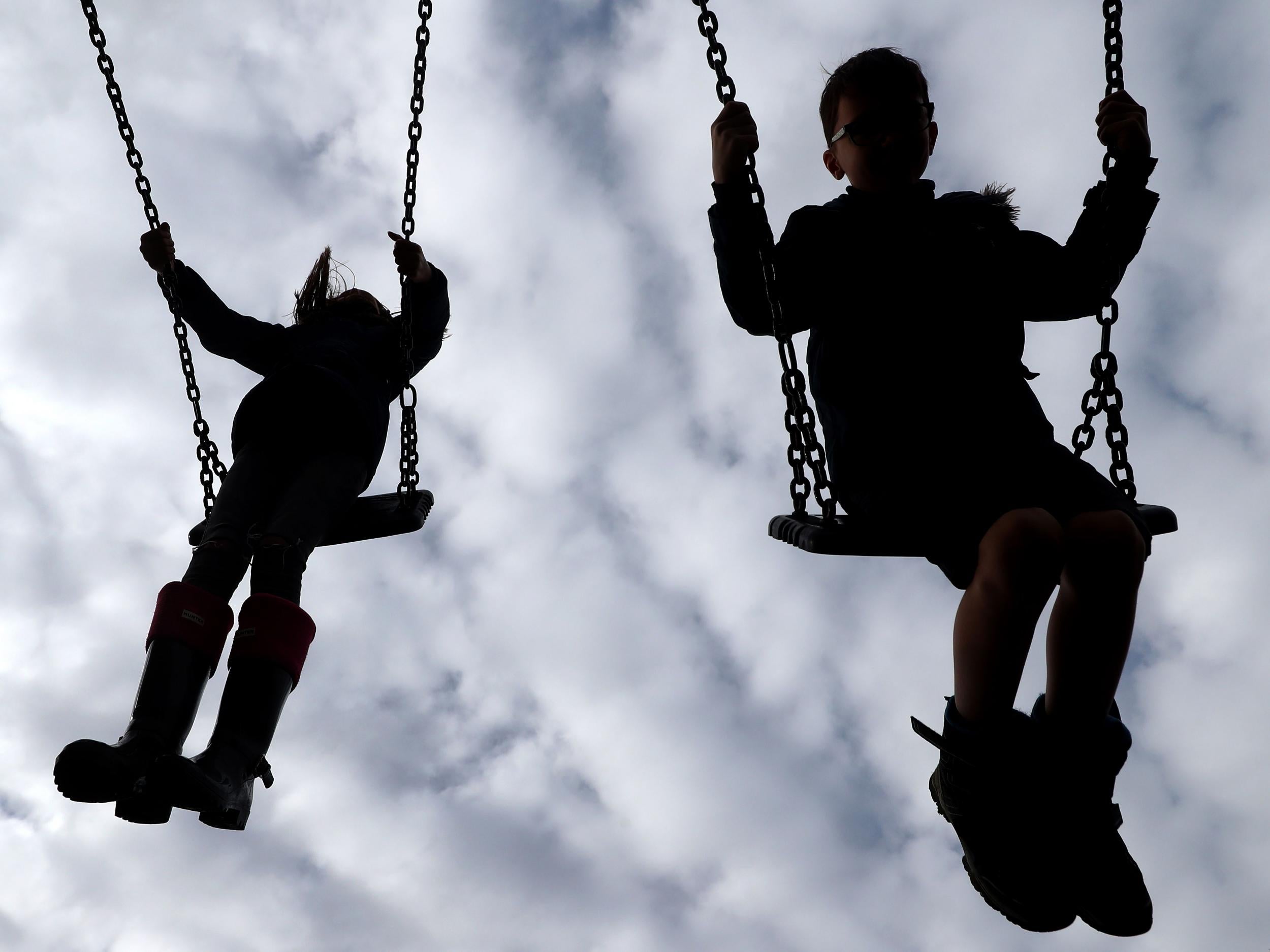 Stock image of children playing on the swings