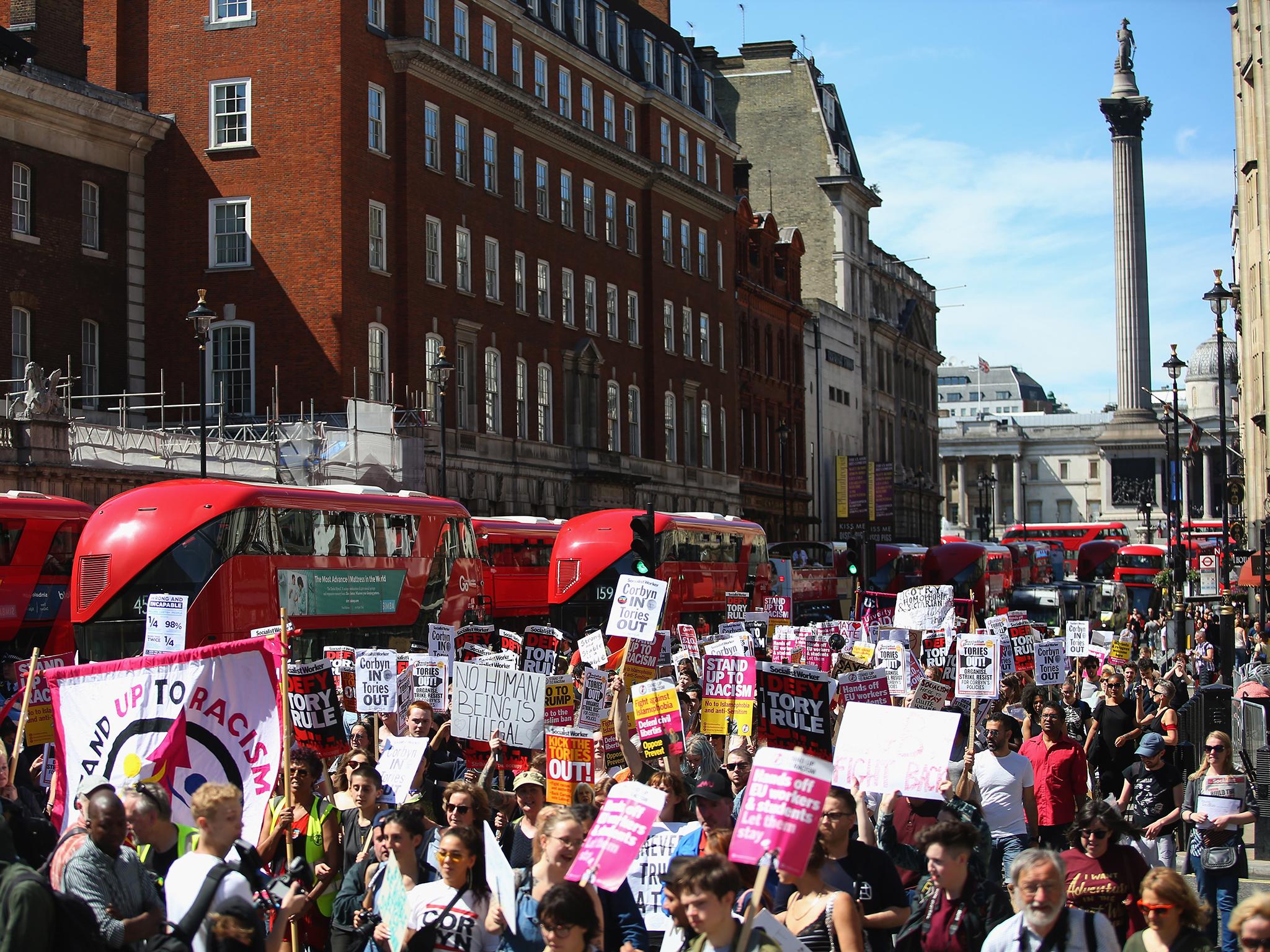 Protesters hold placards as they march against the Conservative party alliance with the DUP on Whitehall